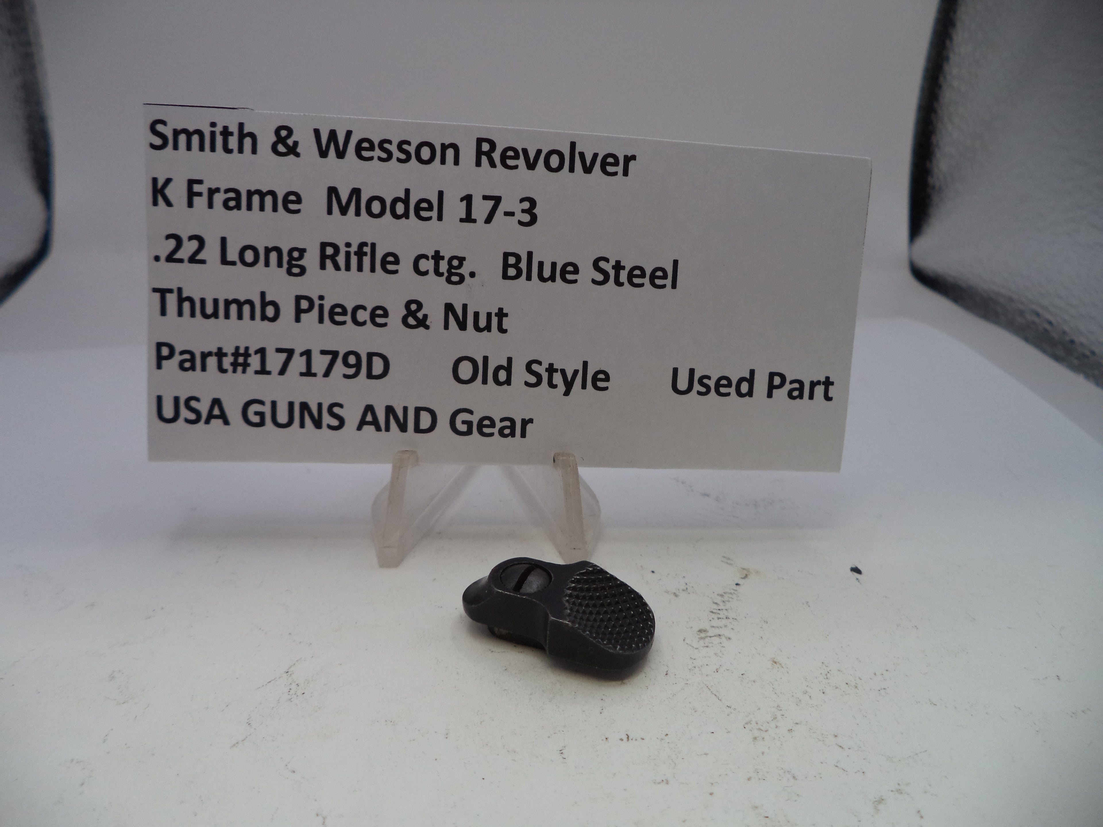 Small black thumb piece and nut with a label on a white surface