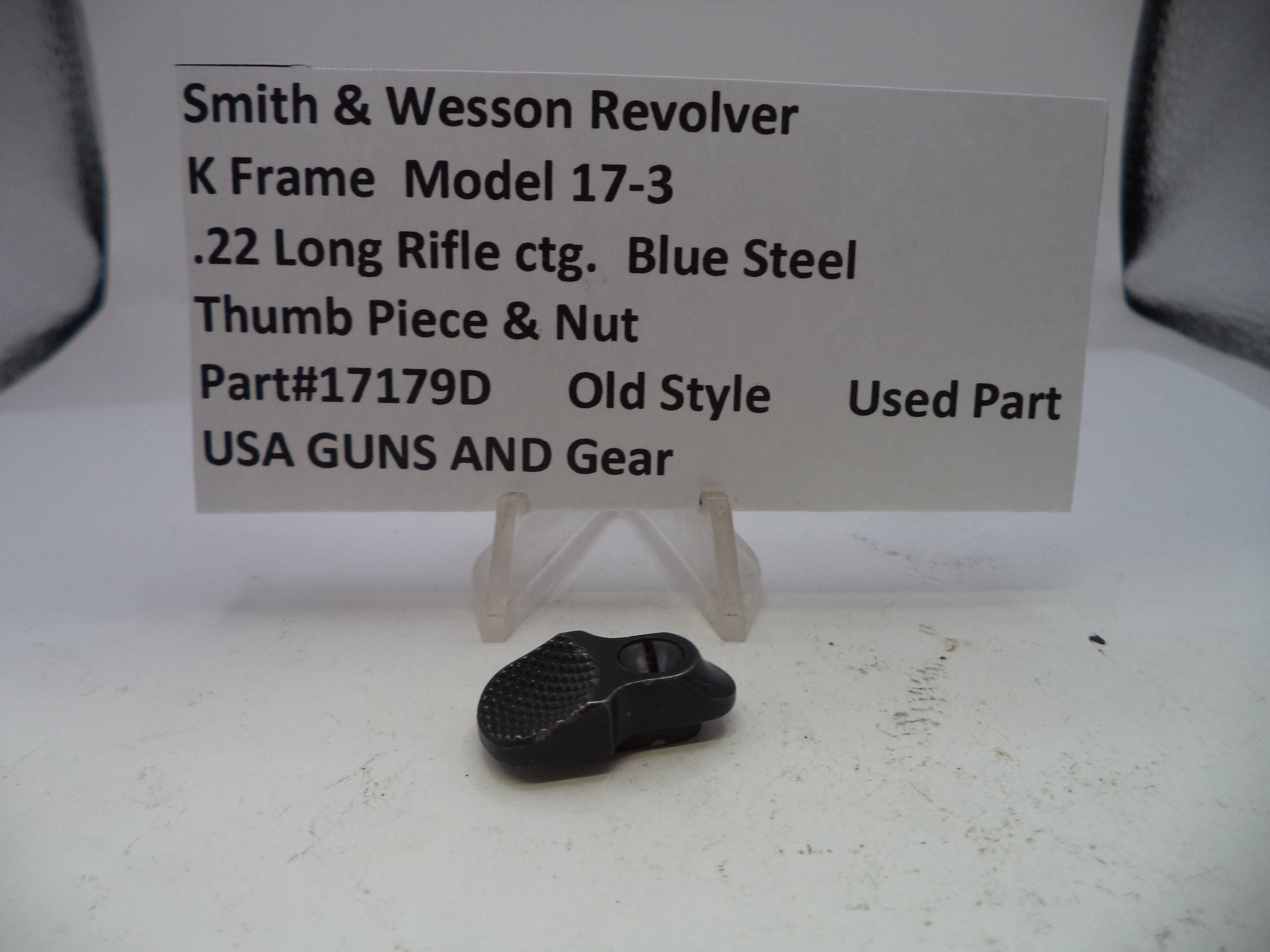 Small black metal part on a white surface with descriptive text card.