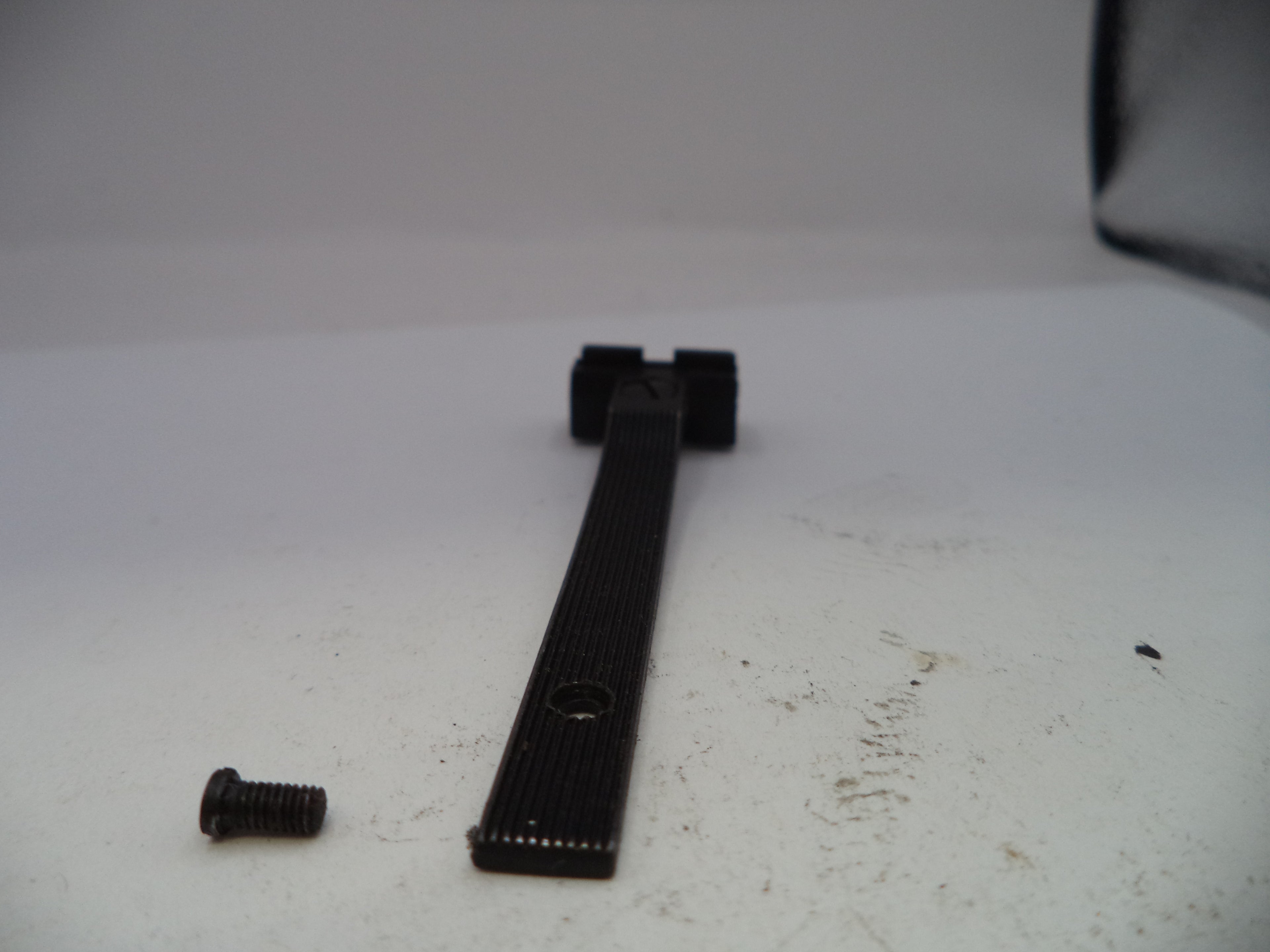 Black metal tool or component on a white surface with visible wear.
