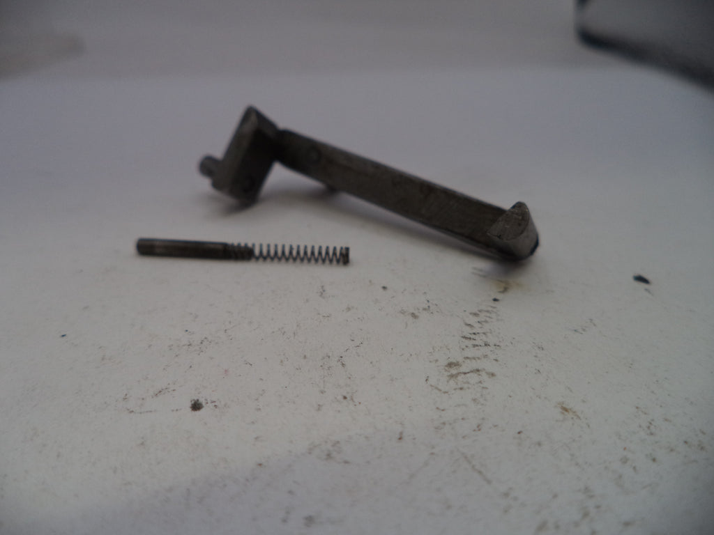 Metal lever and spring on a white surface with visible dirt