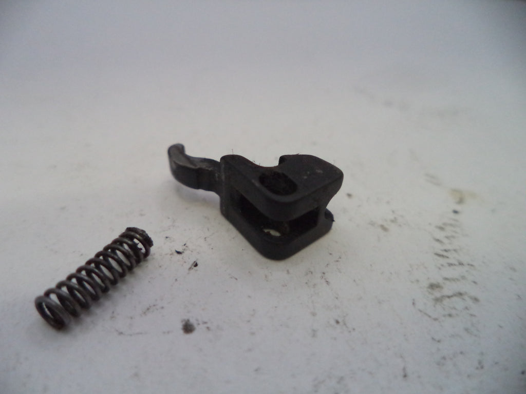 Black plastic component and spring on a white surface