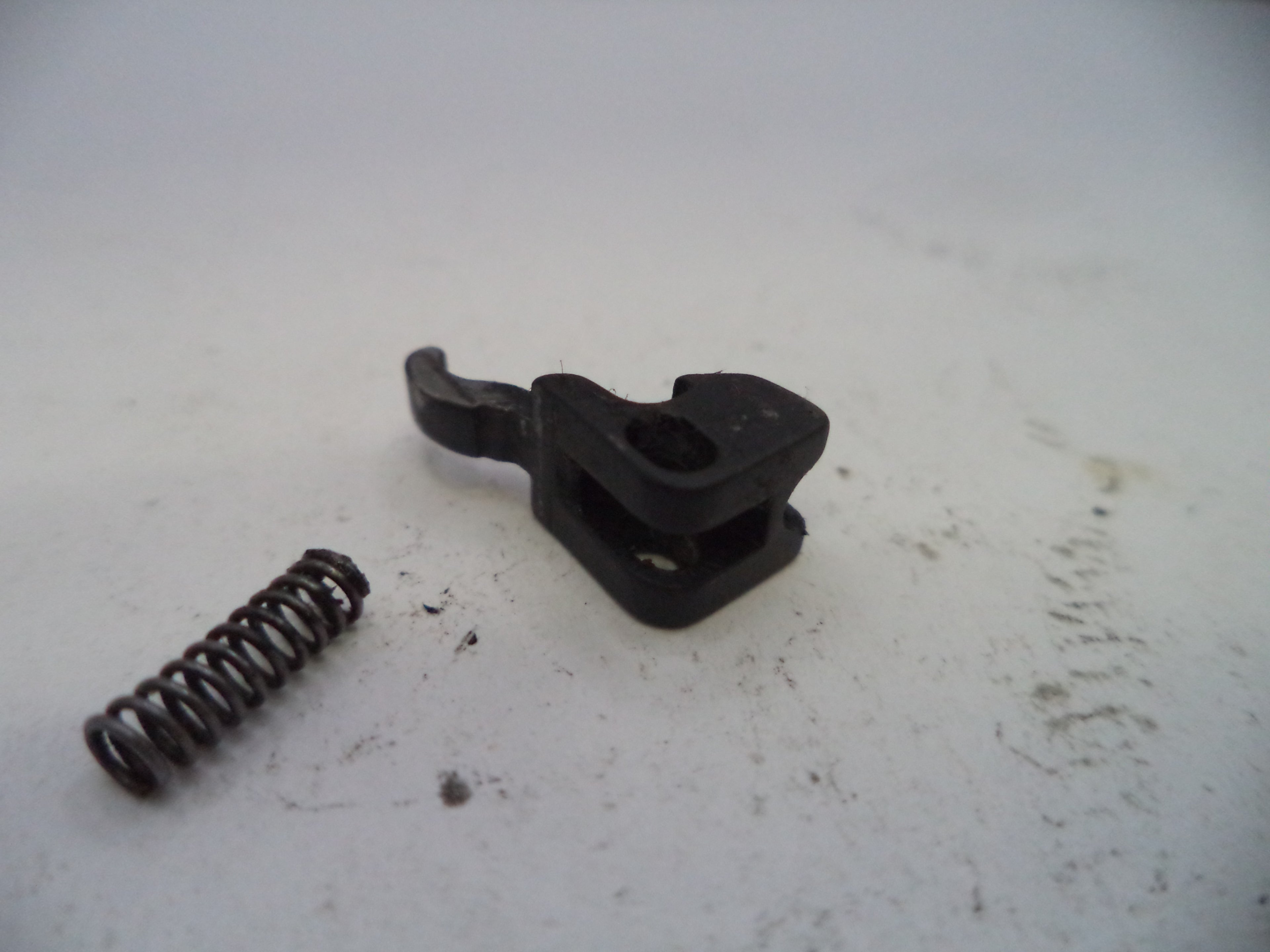 Black plastic component and spring on a white surface