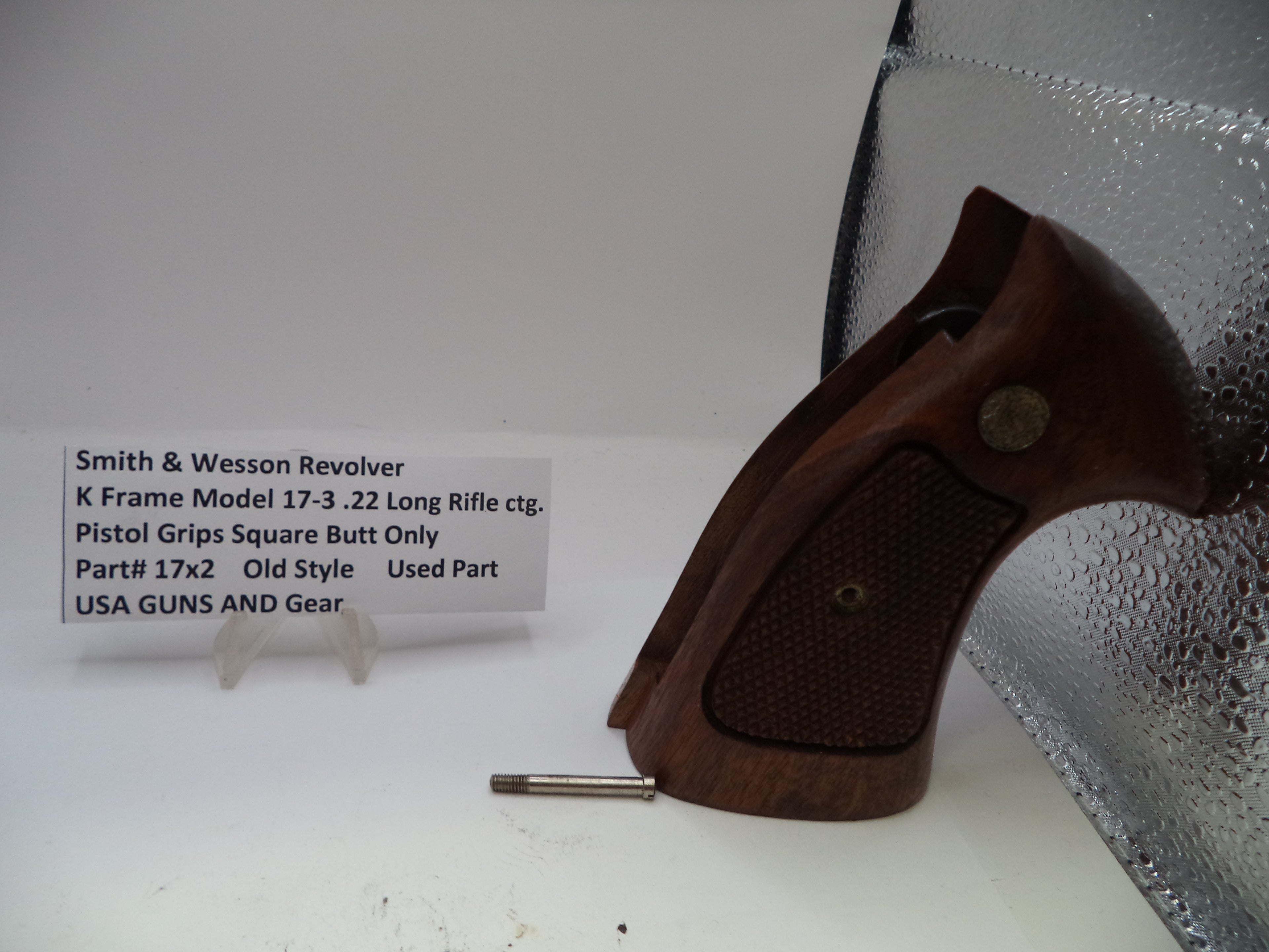 Wooden pistol grip on a white surface with a label in the background.