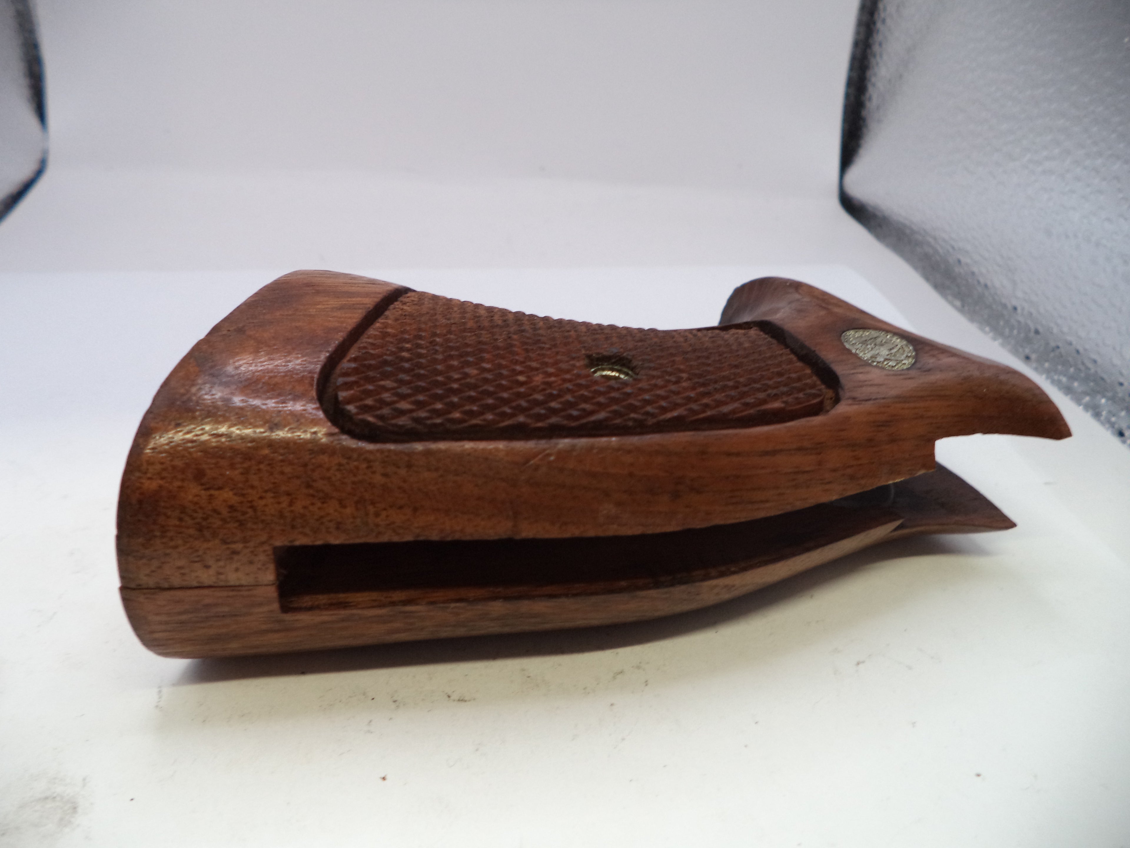 Wooden gun stock on a white surface with a gray background
