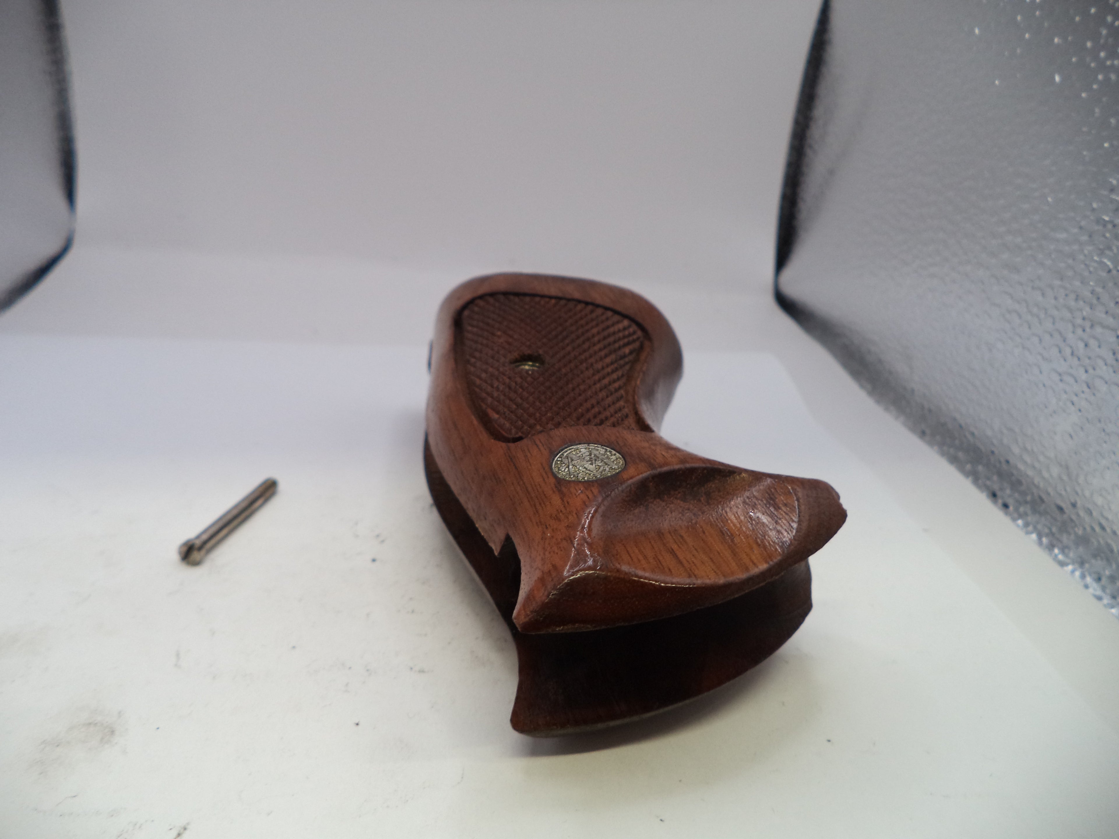 Wooden gun stock with metal screw on a white surface