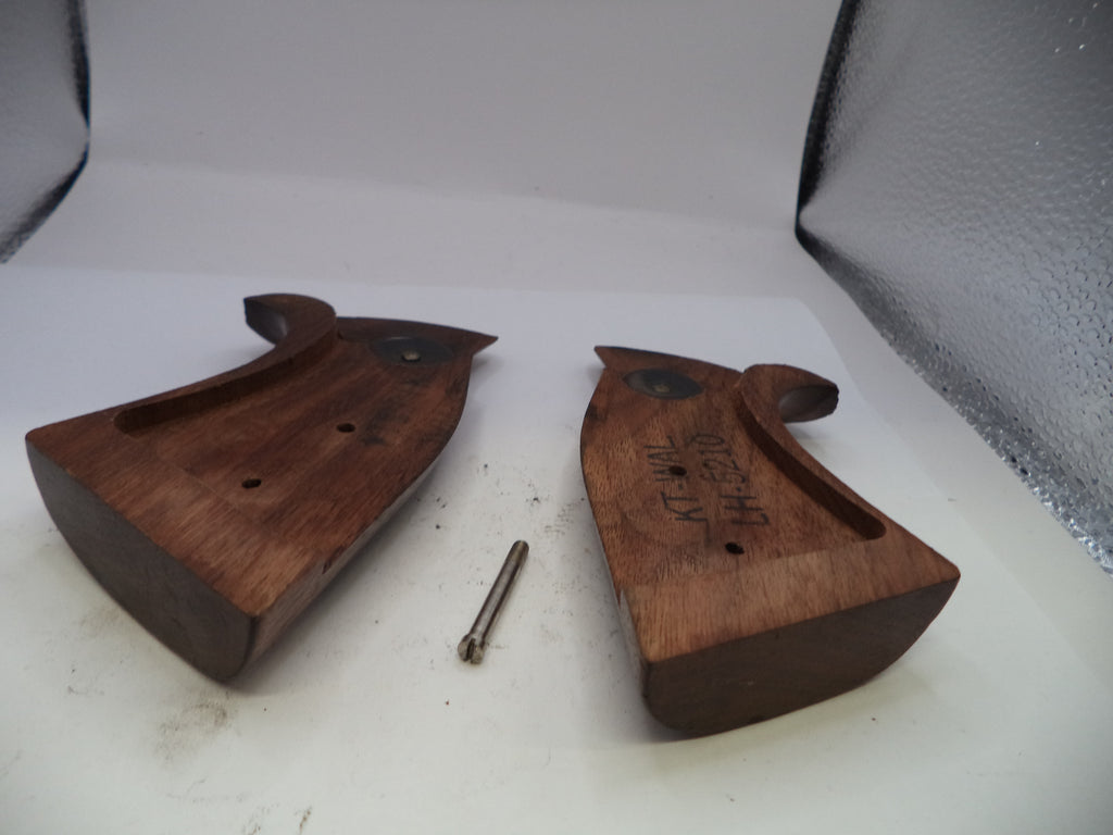 Two wooden gun grips with a screw on a white surface