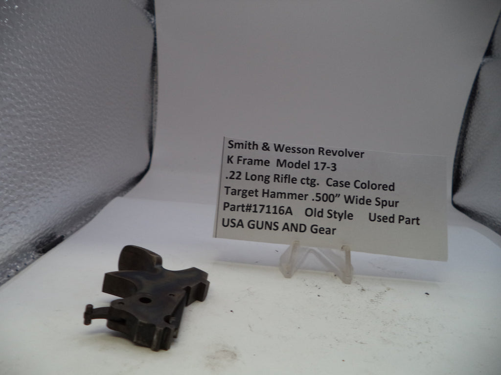 Black gun part on a white surface with a descriptive card in the background