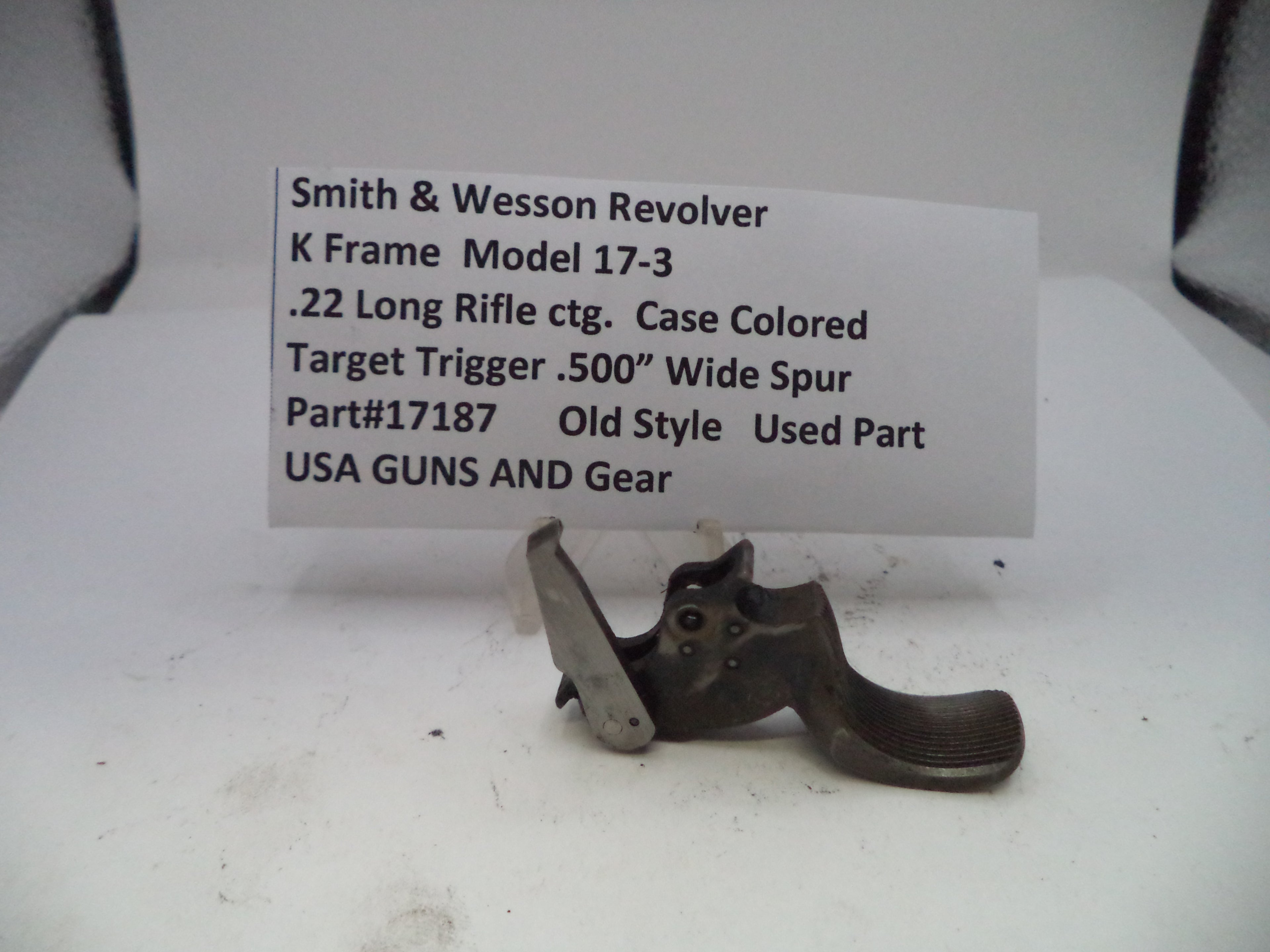 Smith & Wesson revolver trigger part with descriptive label on a white background