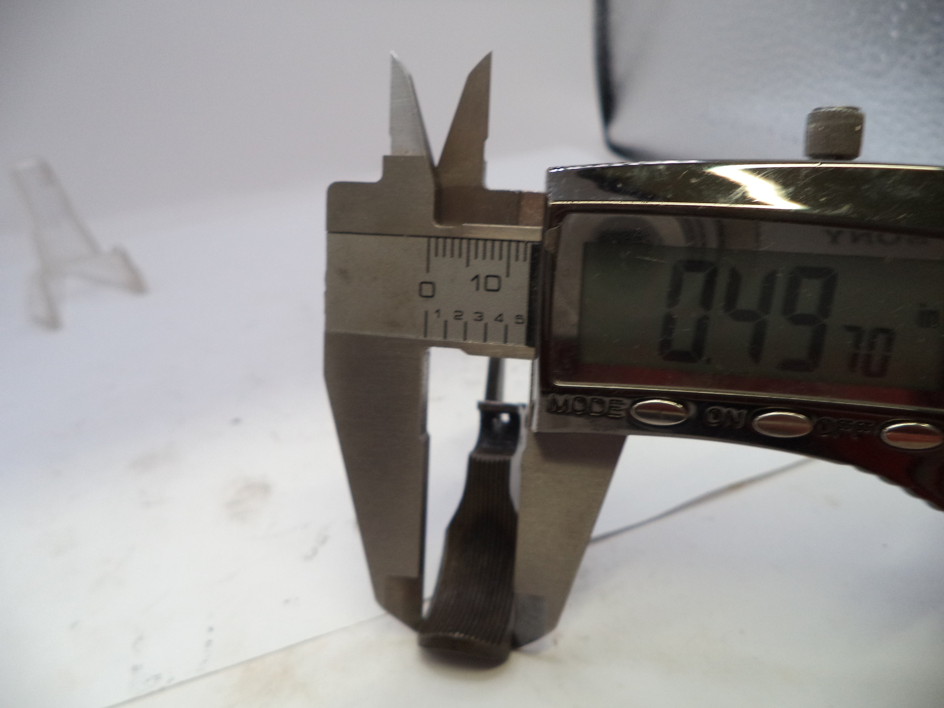Digital caliper measuring a small metal object on a white background