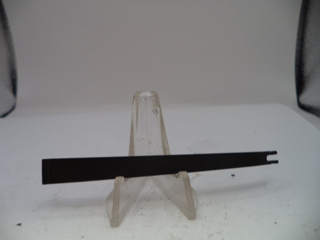 Long black rectangular object on a clear stand against a white background