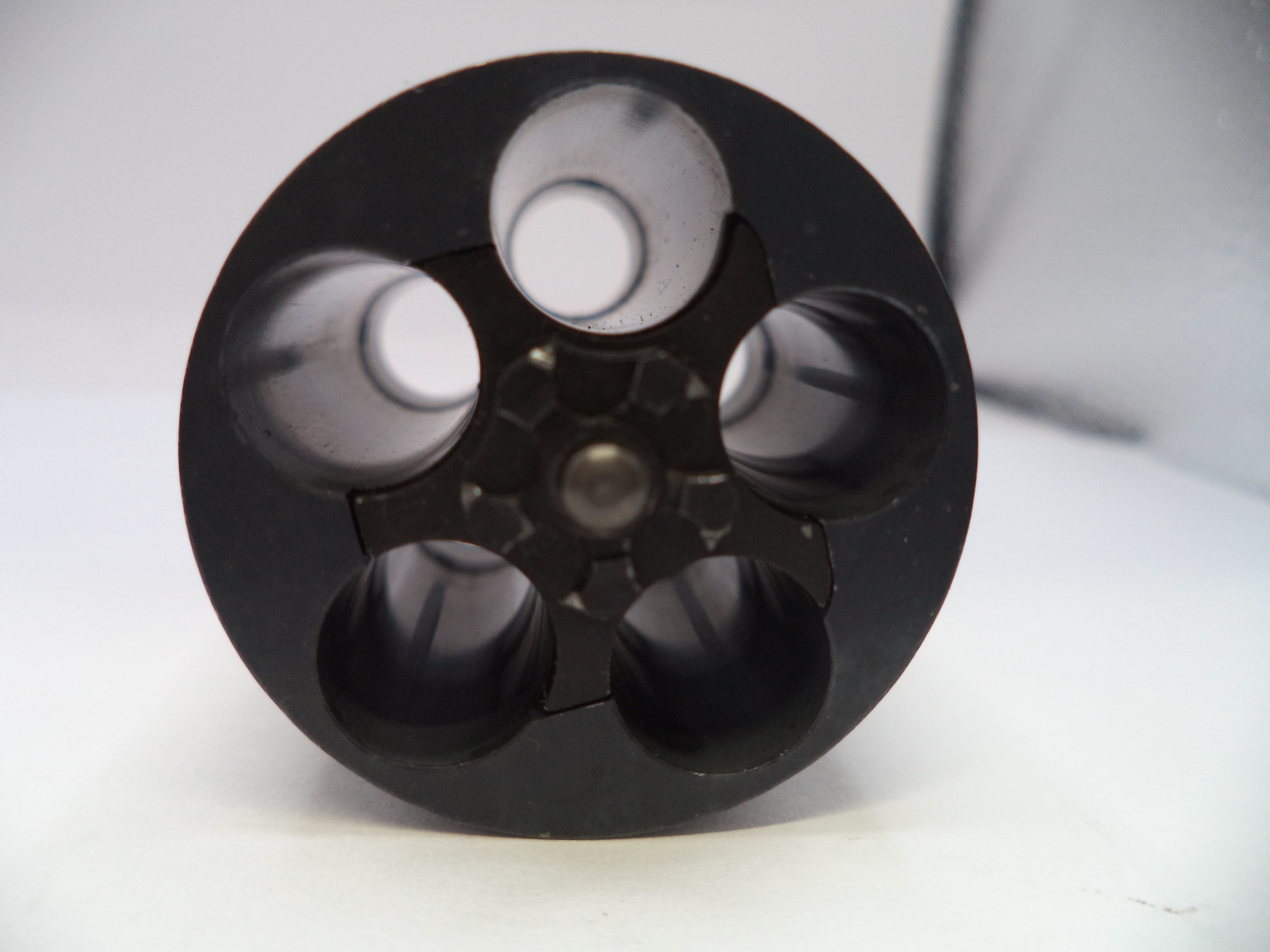 Black cylindrical object with multiple compartments on a white background