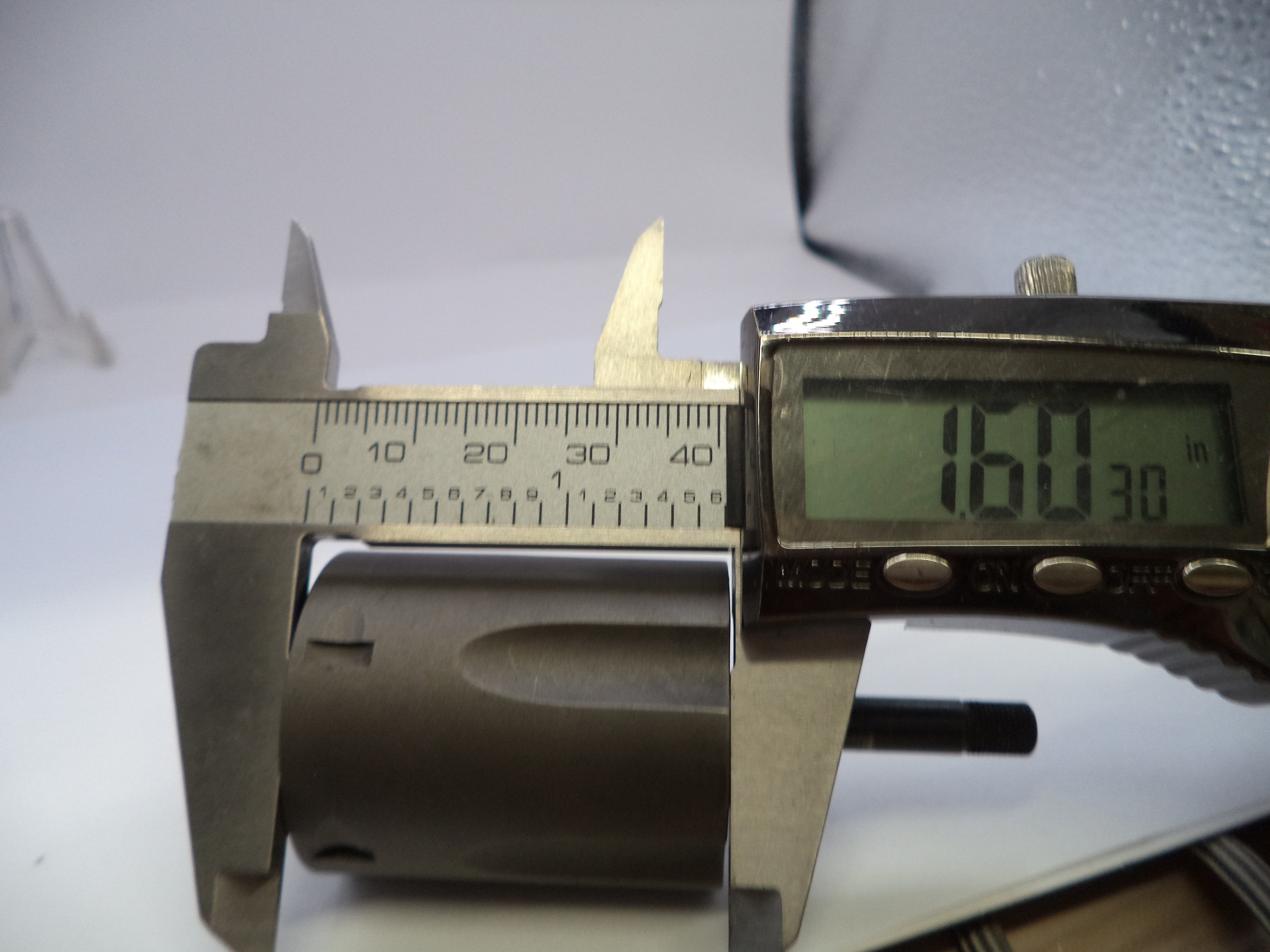Digital caliper measuring a cylindrical object with a digital display showing measurement.