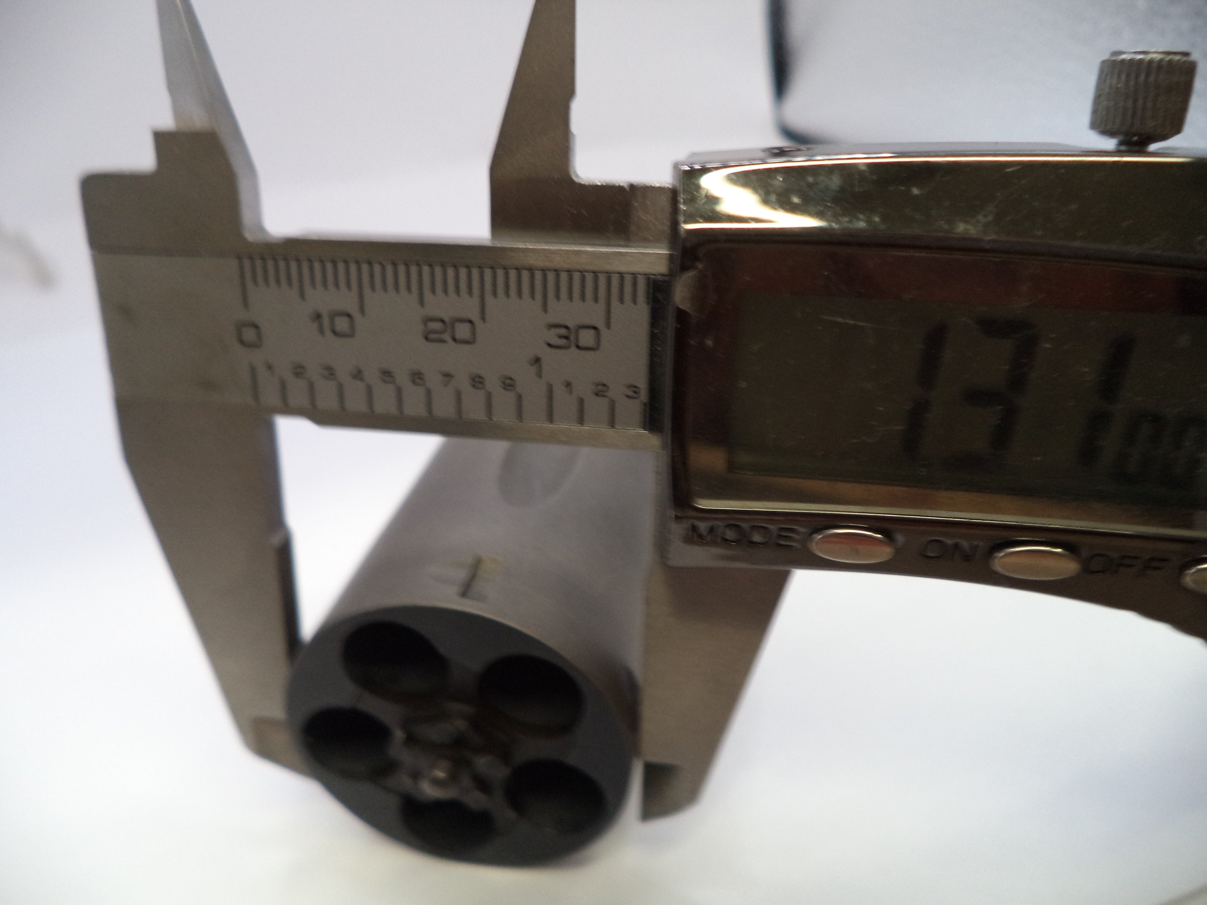 Digital caliper measuring a cylindrical object on a white background