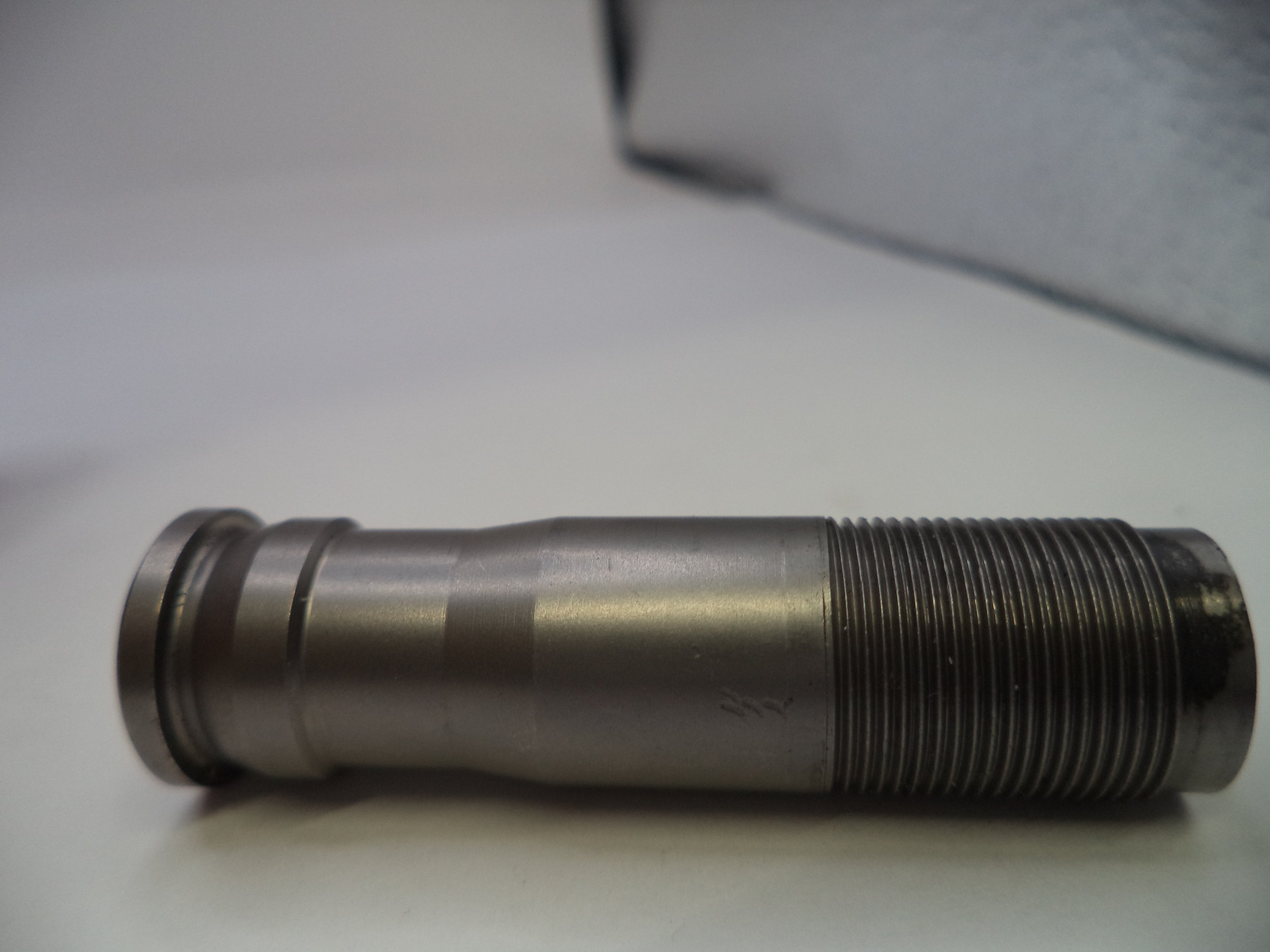 Metal cylindrical object with threaded end on a white surface