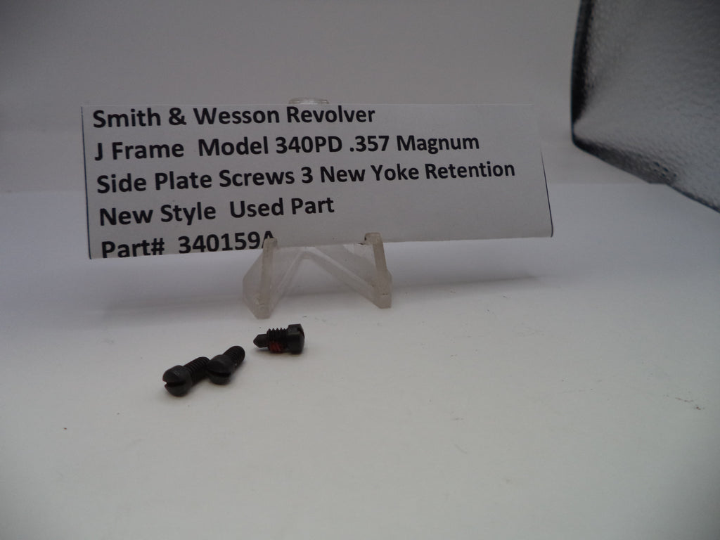 Two screws on a white surface with a label describing a Smith & Wesson revolver part.