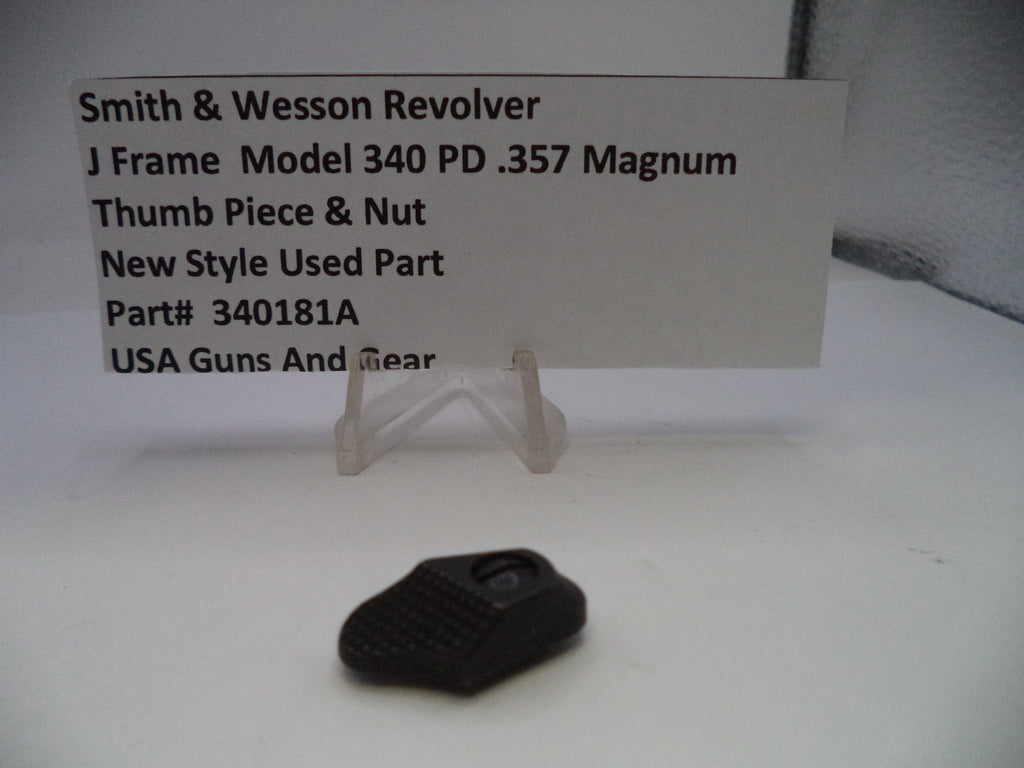 Black gun part on a white surface with a descriptive card behind it.