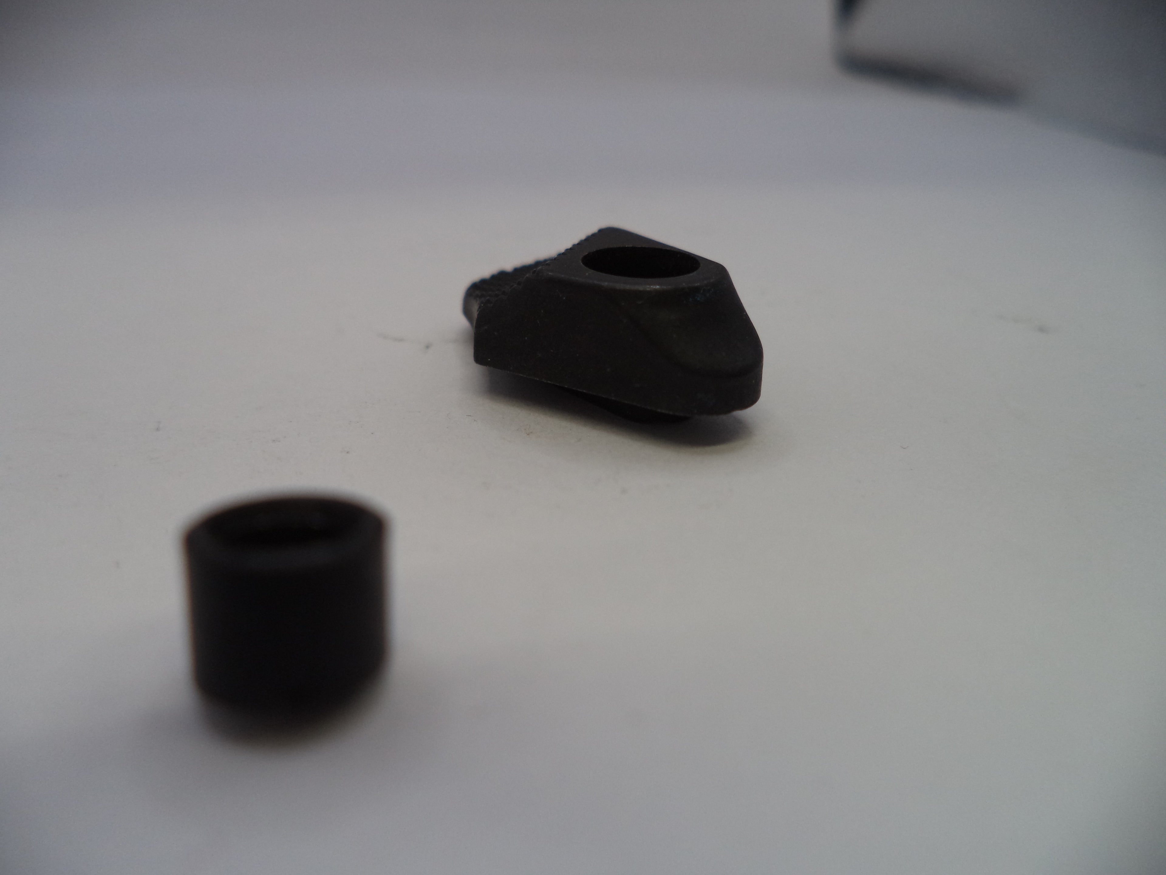 Two black rubber grommets on a white surface