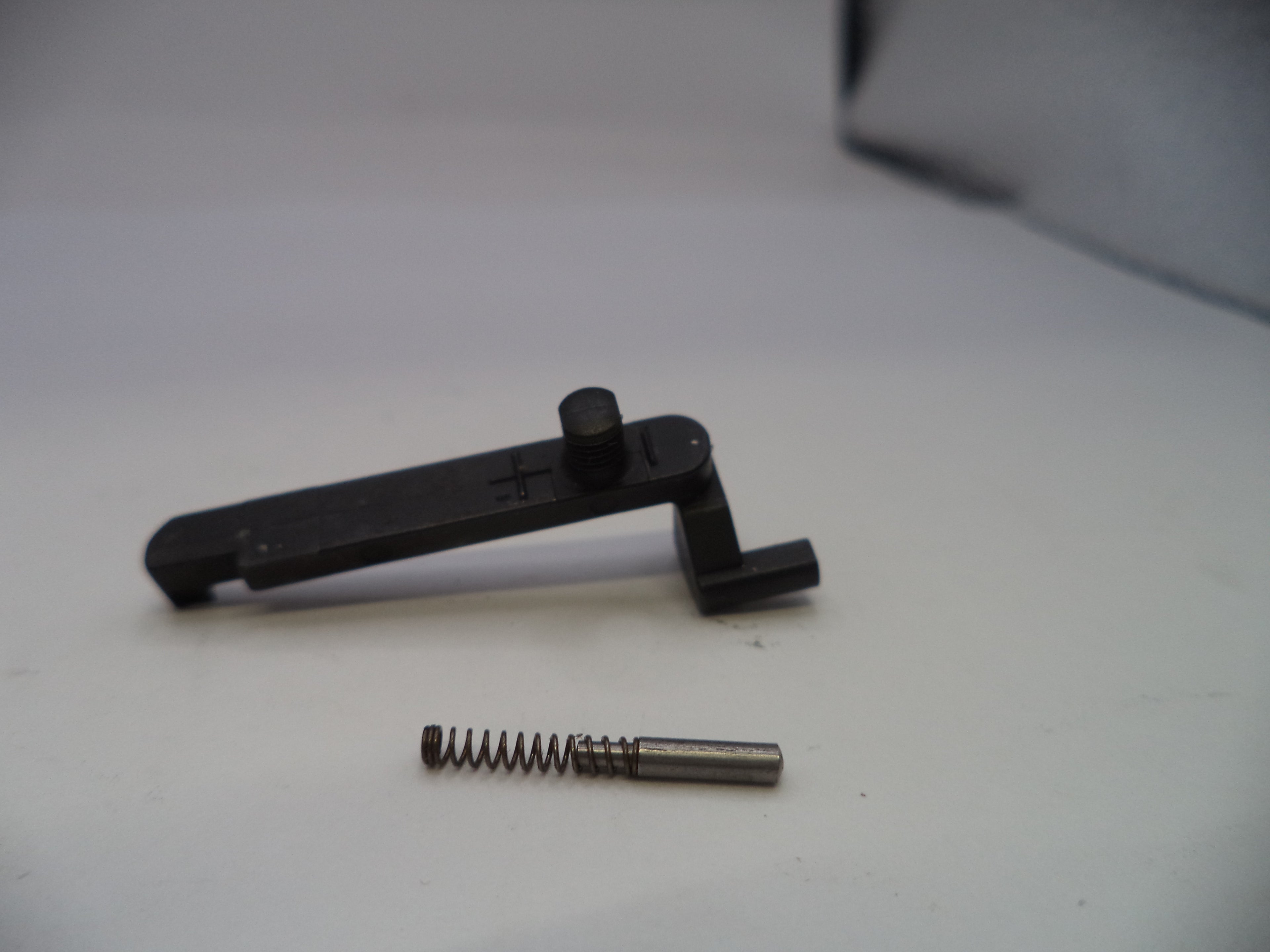 Black metal tool and spring on a white surface