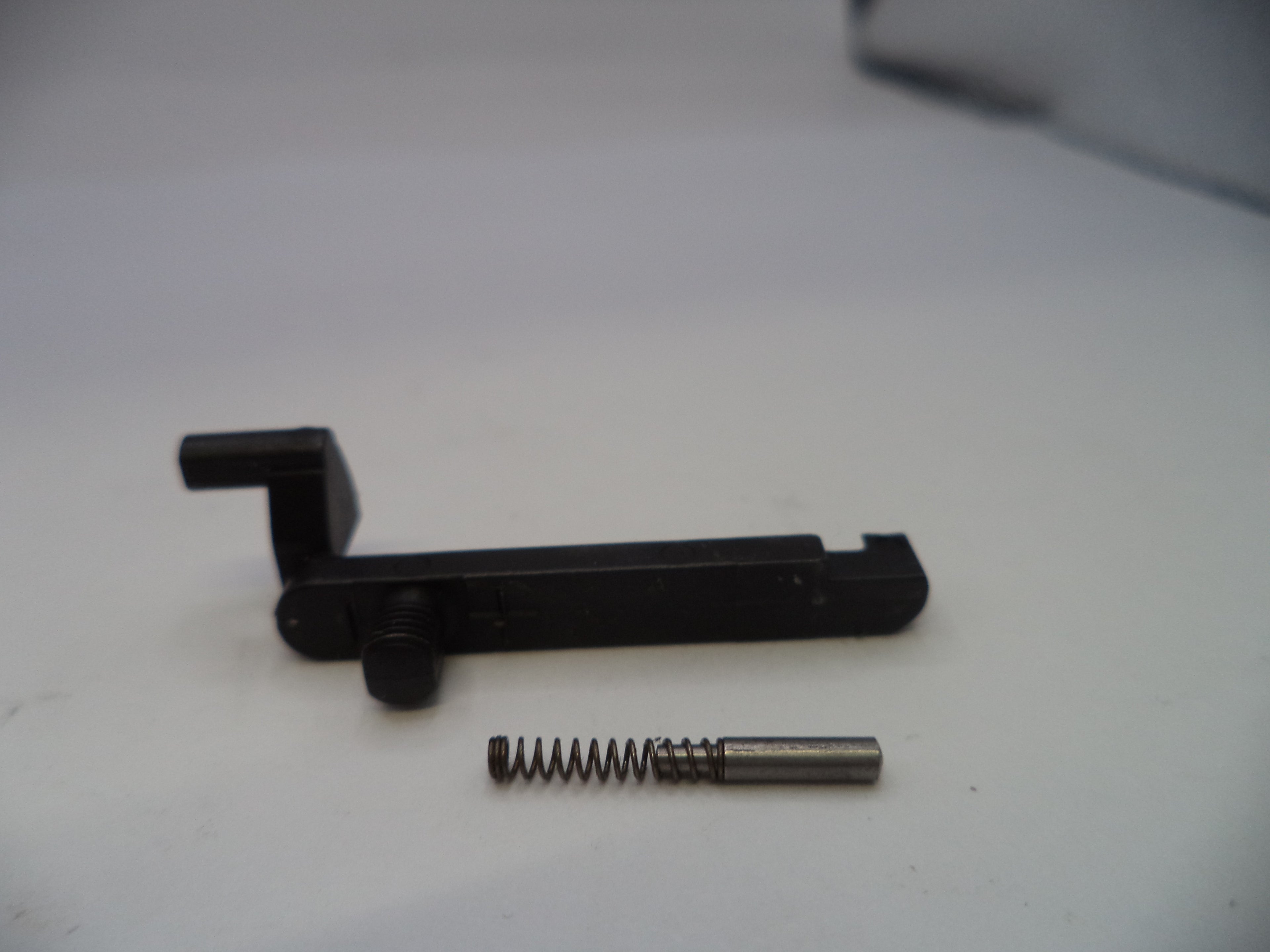 Black metal component with a spring on a white surface
