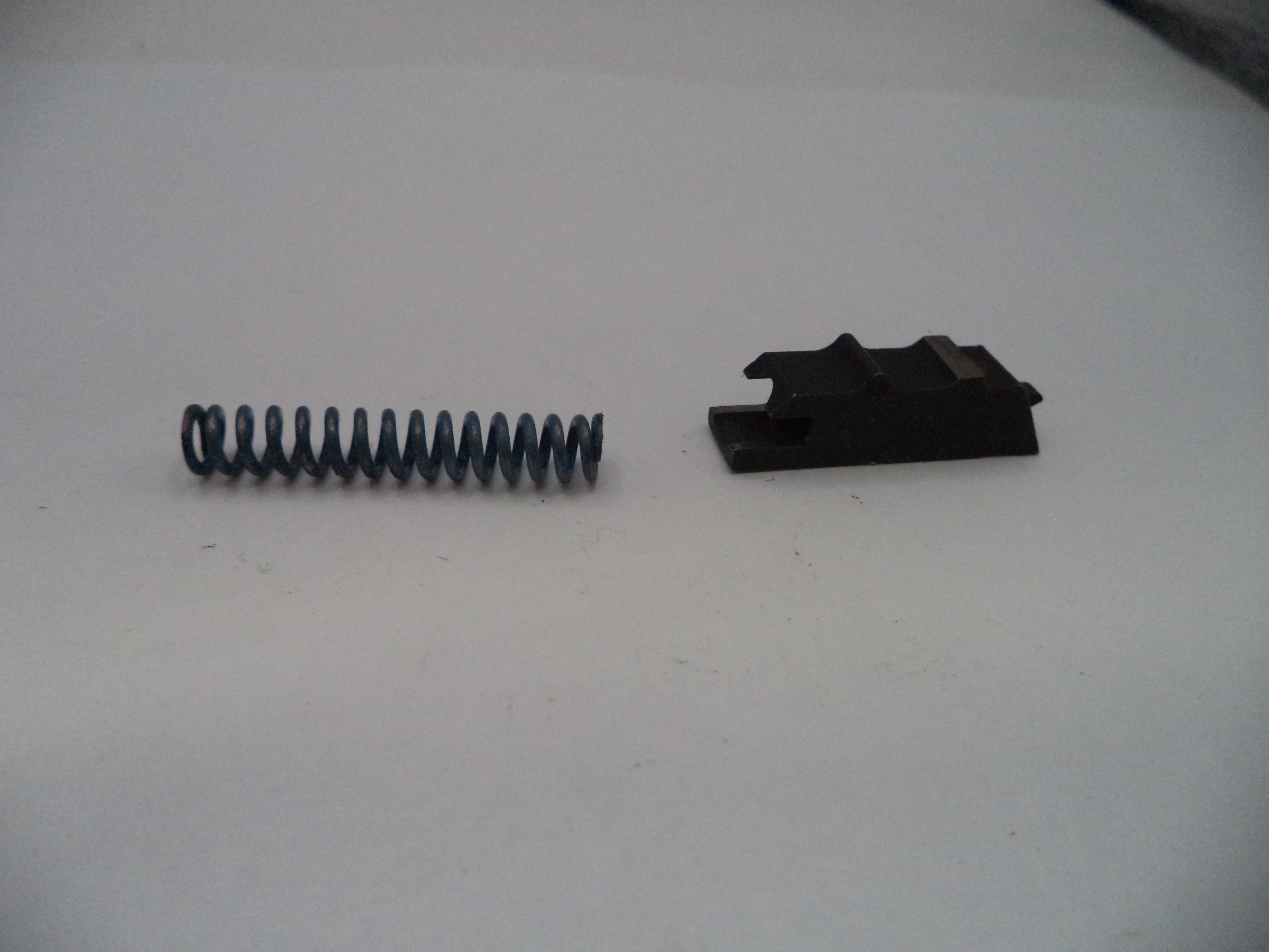 Black spring and black metal bracket on a white surface