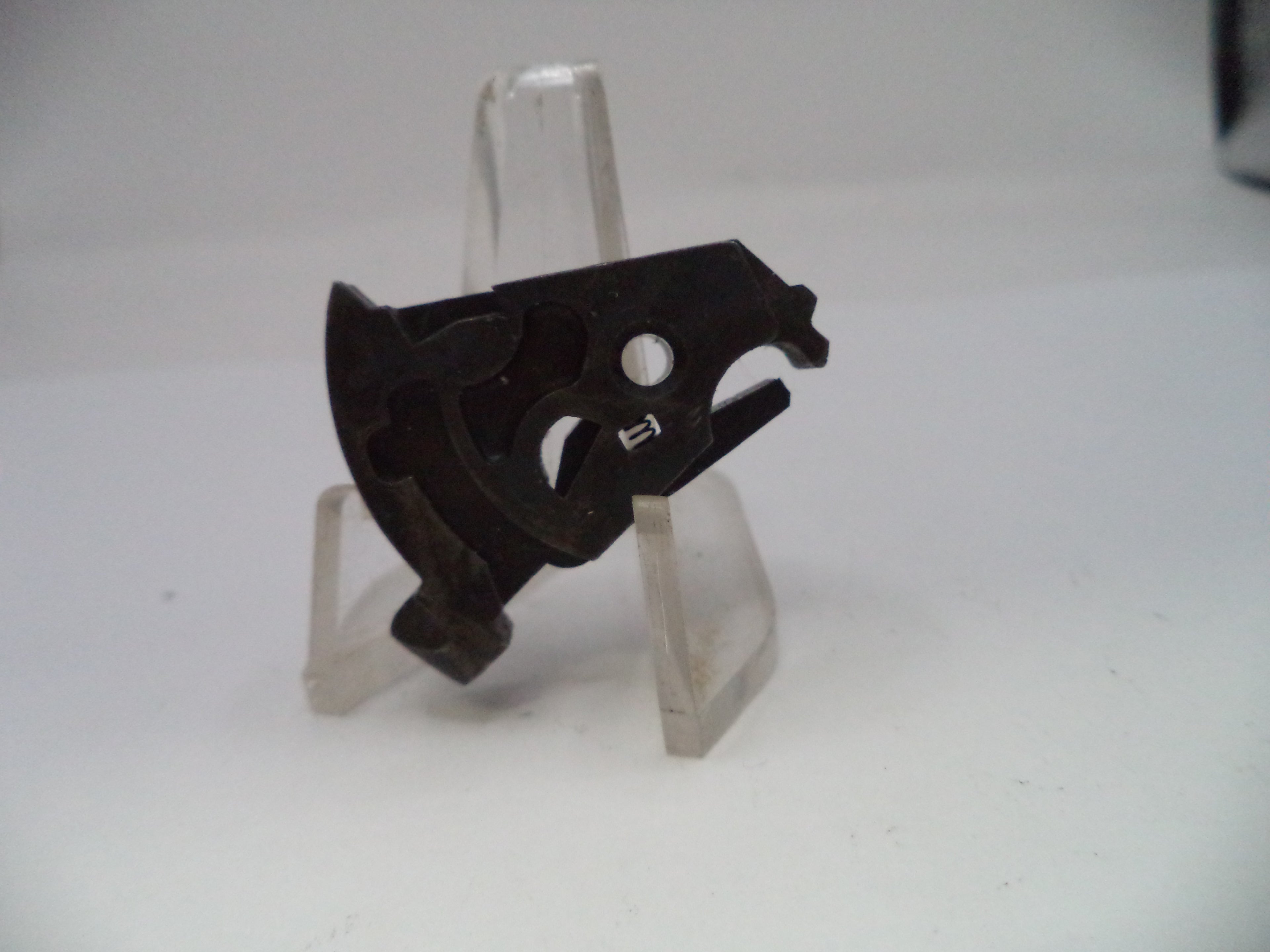 Black metal object on a clear stand against a white background