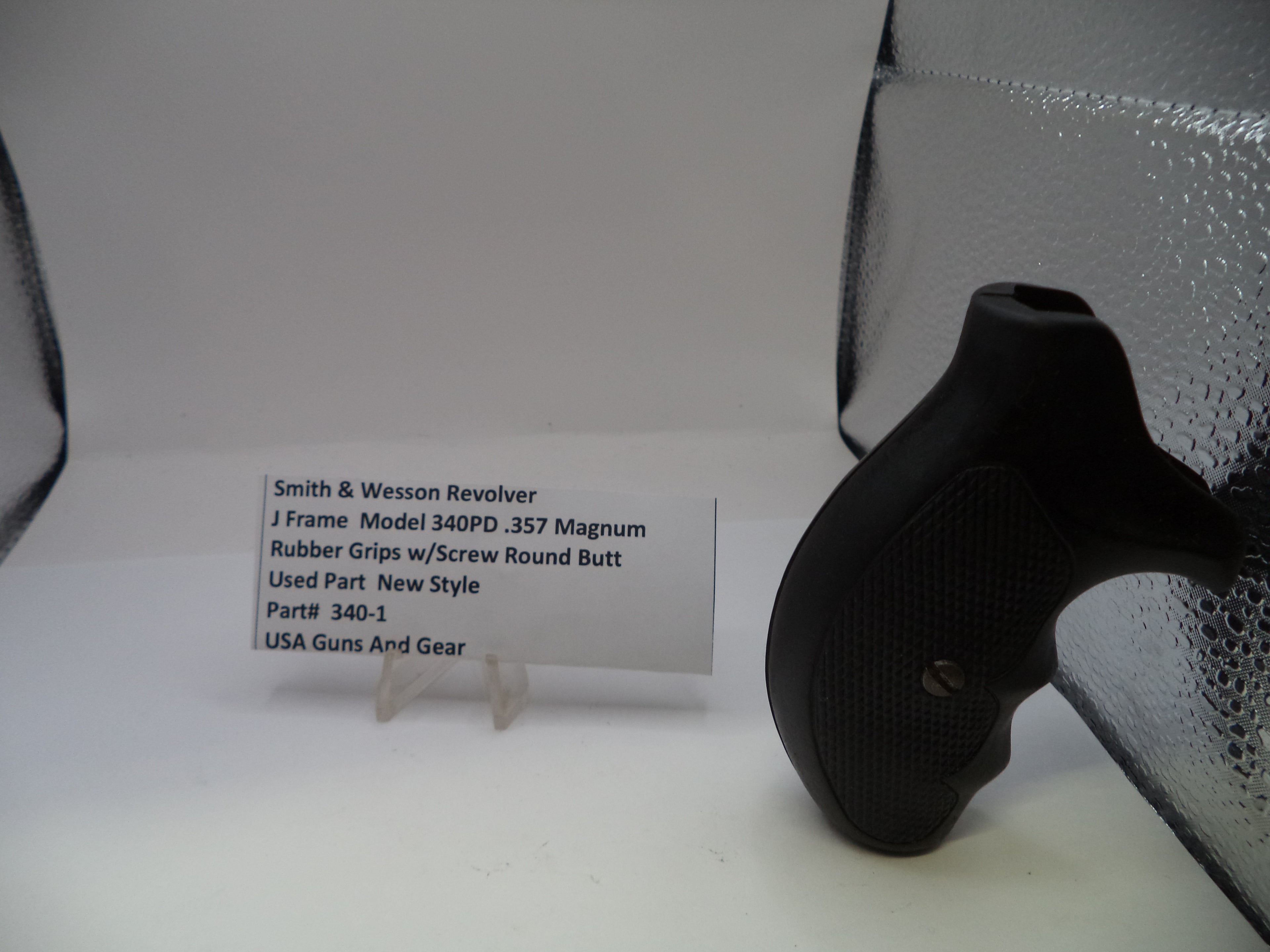 Black gun grip on a white surface with a label in the background