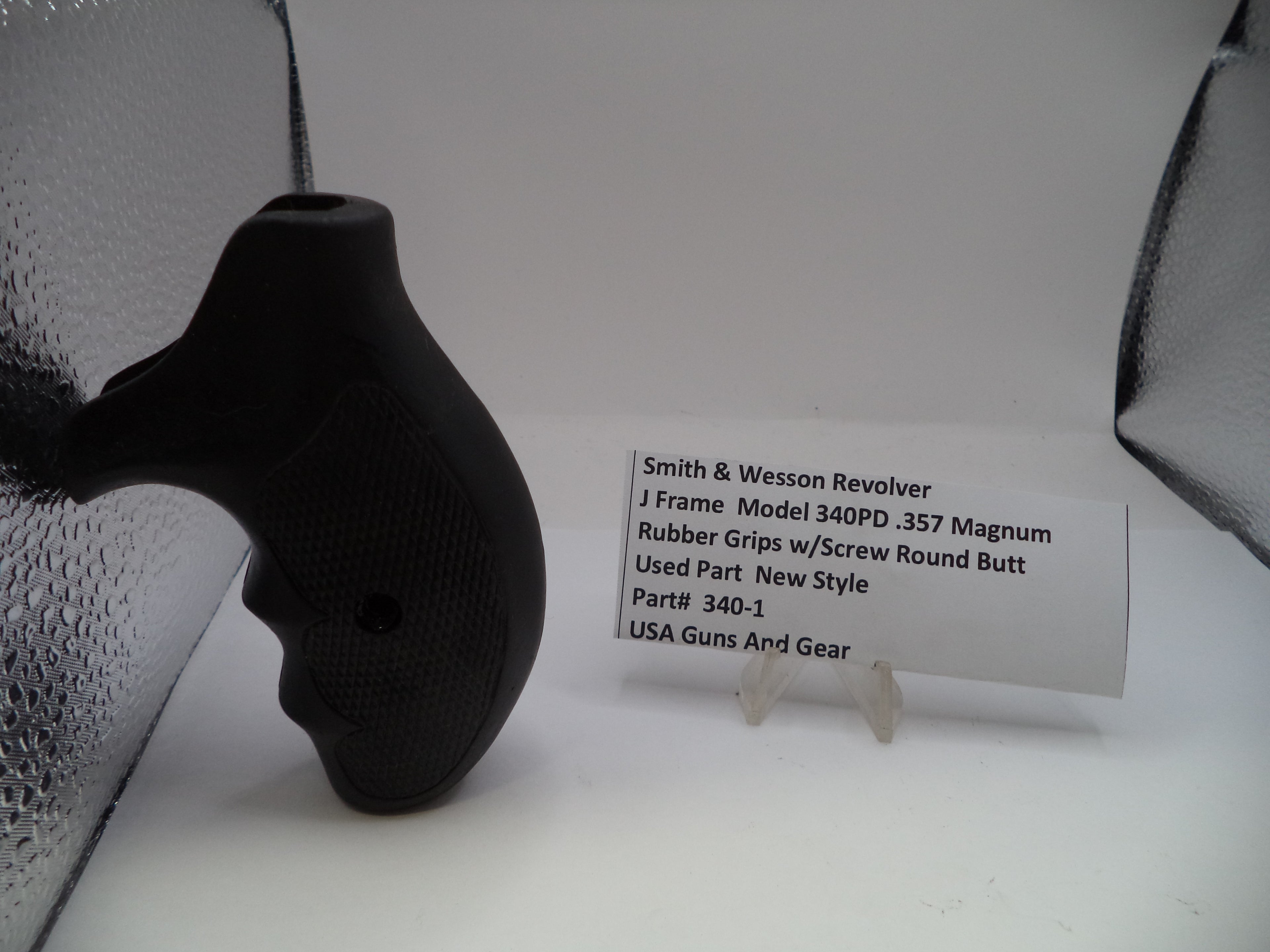 Black revolver with rubber grips on a white background, accompanied by a label.