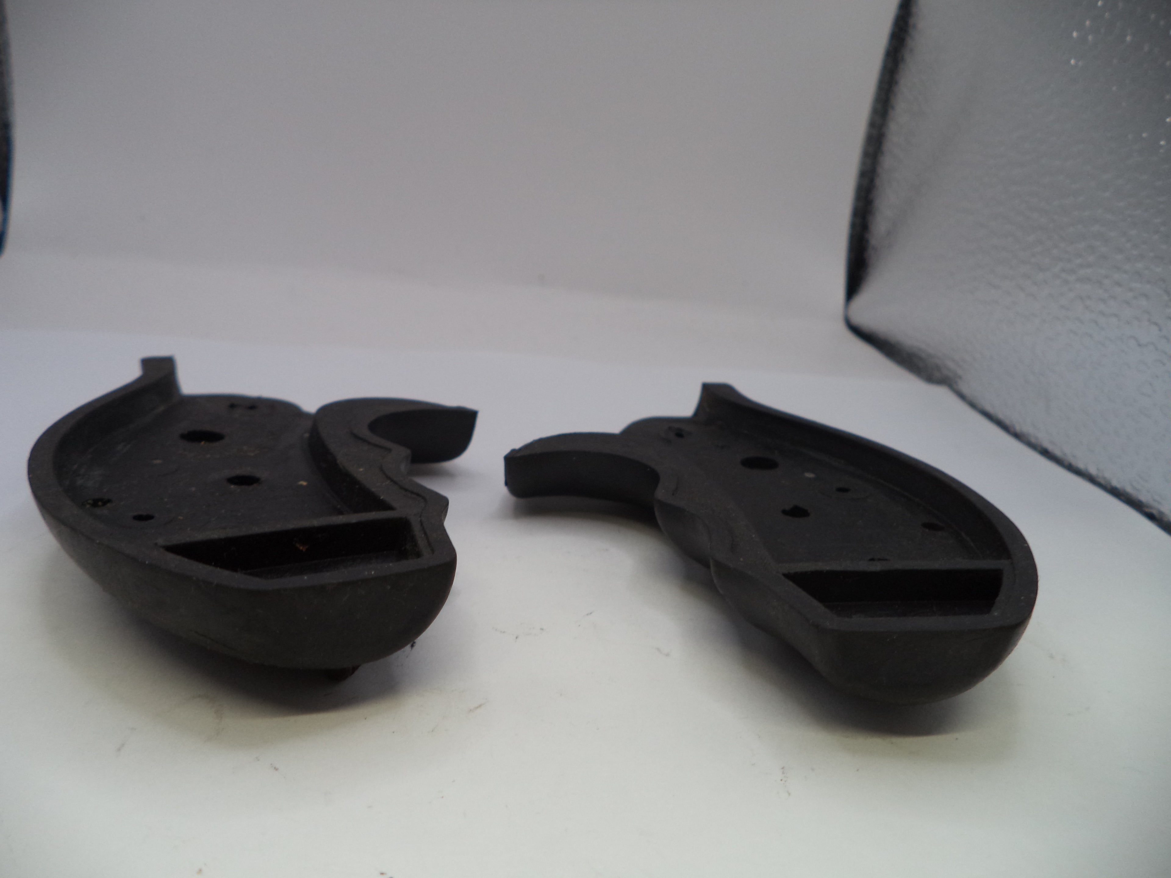 Two black rubber components on a white surface