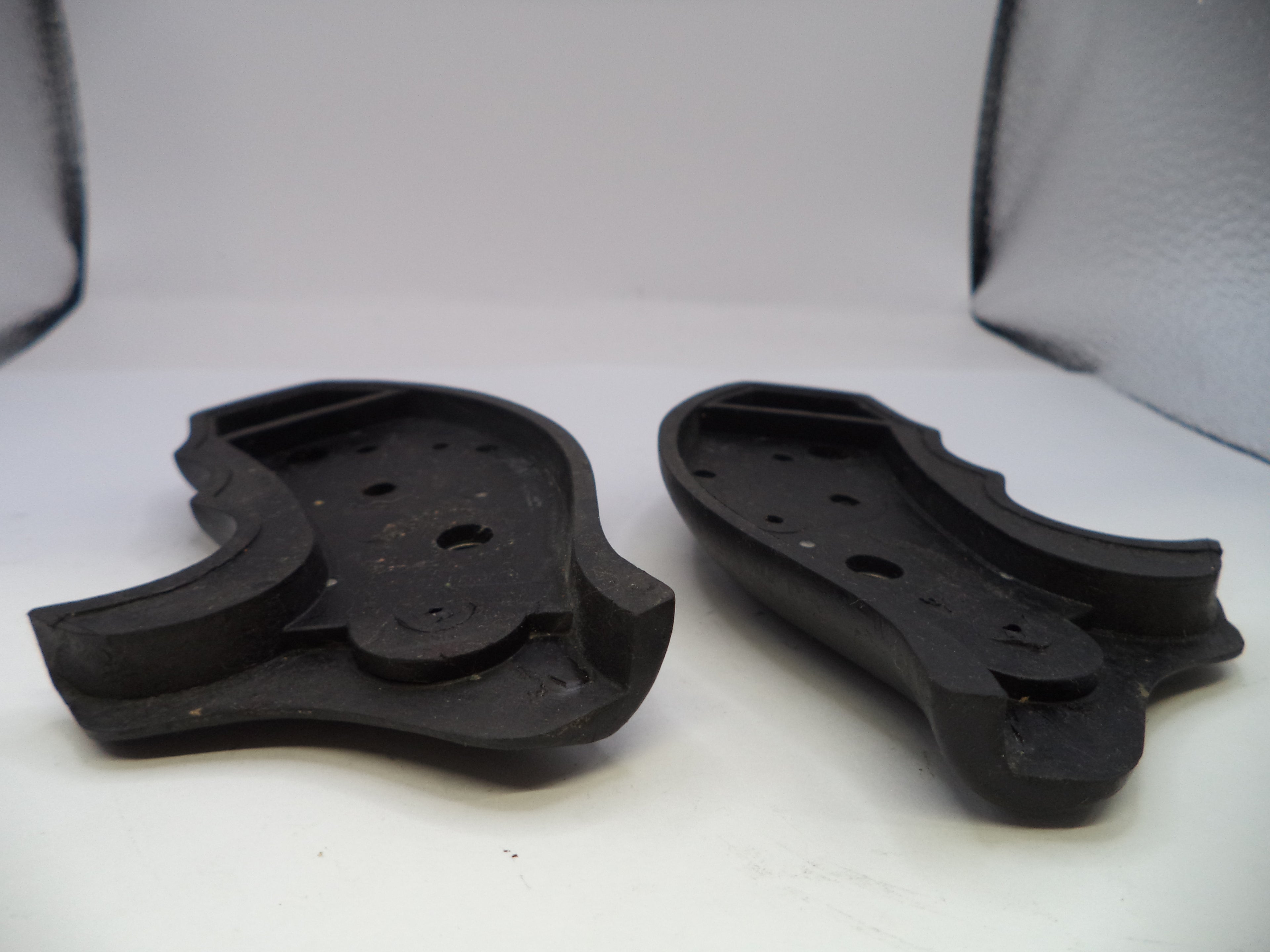 Two black rubber foot pads on a white surface