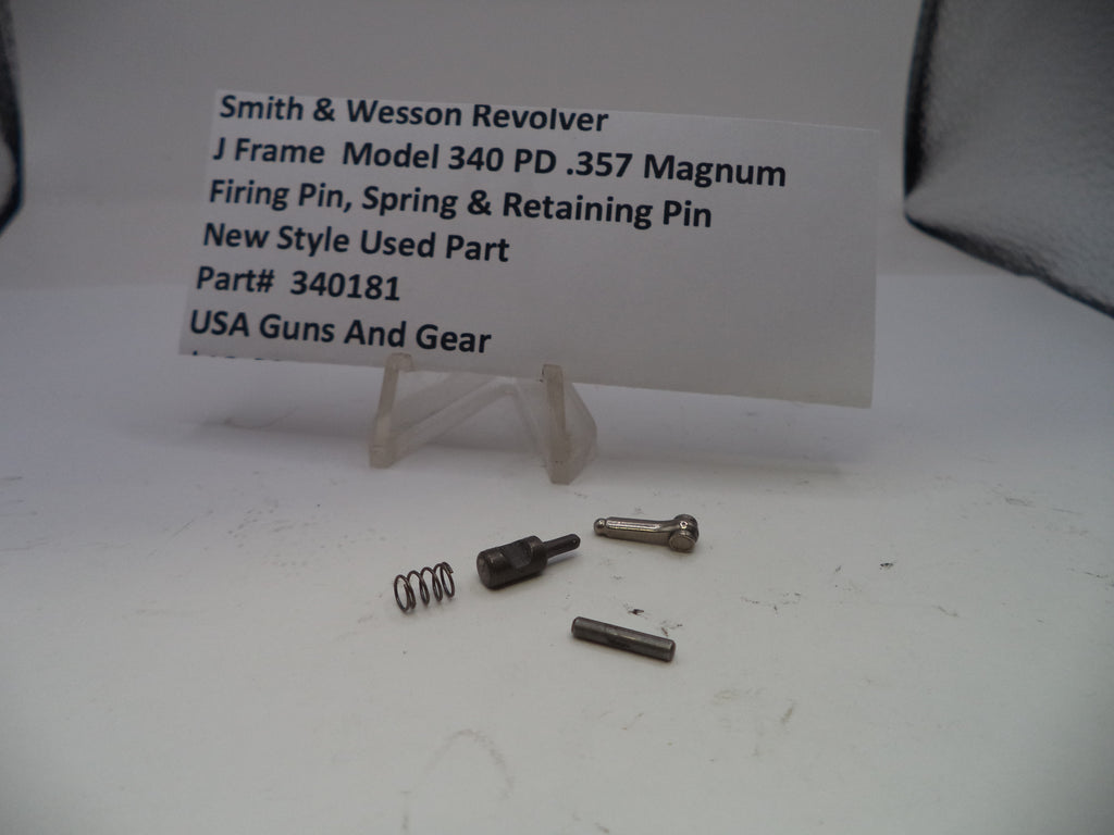 Smith & Wesson revolver parts including a firing pin, spring, and retaining pin on a white surface with a label.