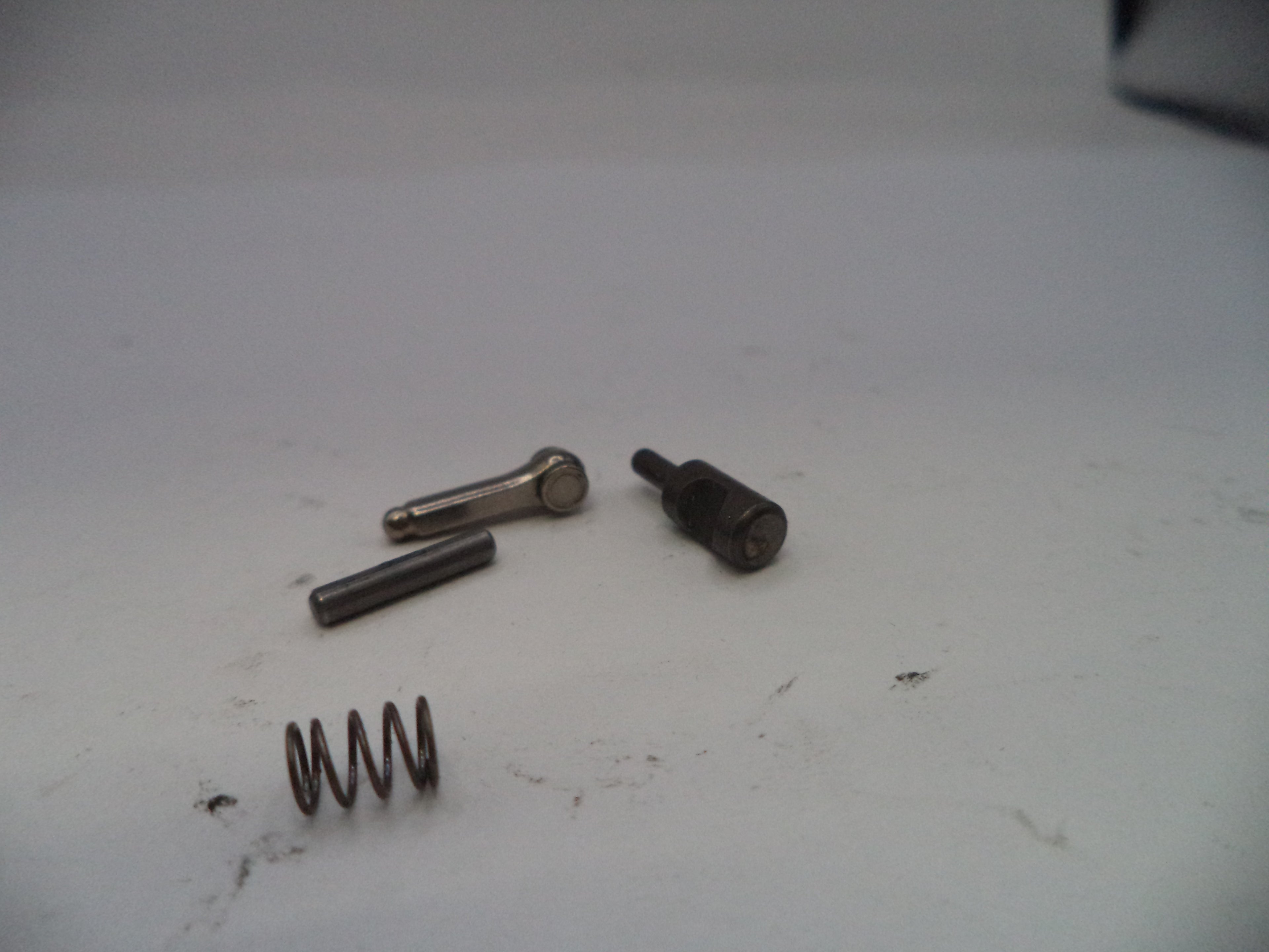 Three metal springs and a bolt on a white surface