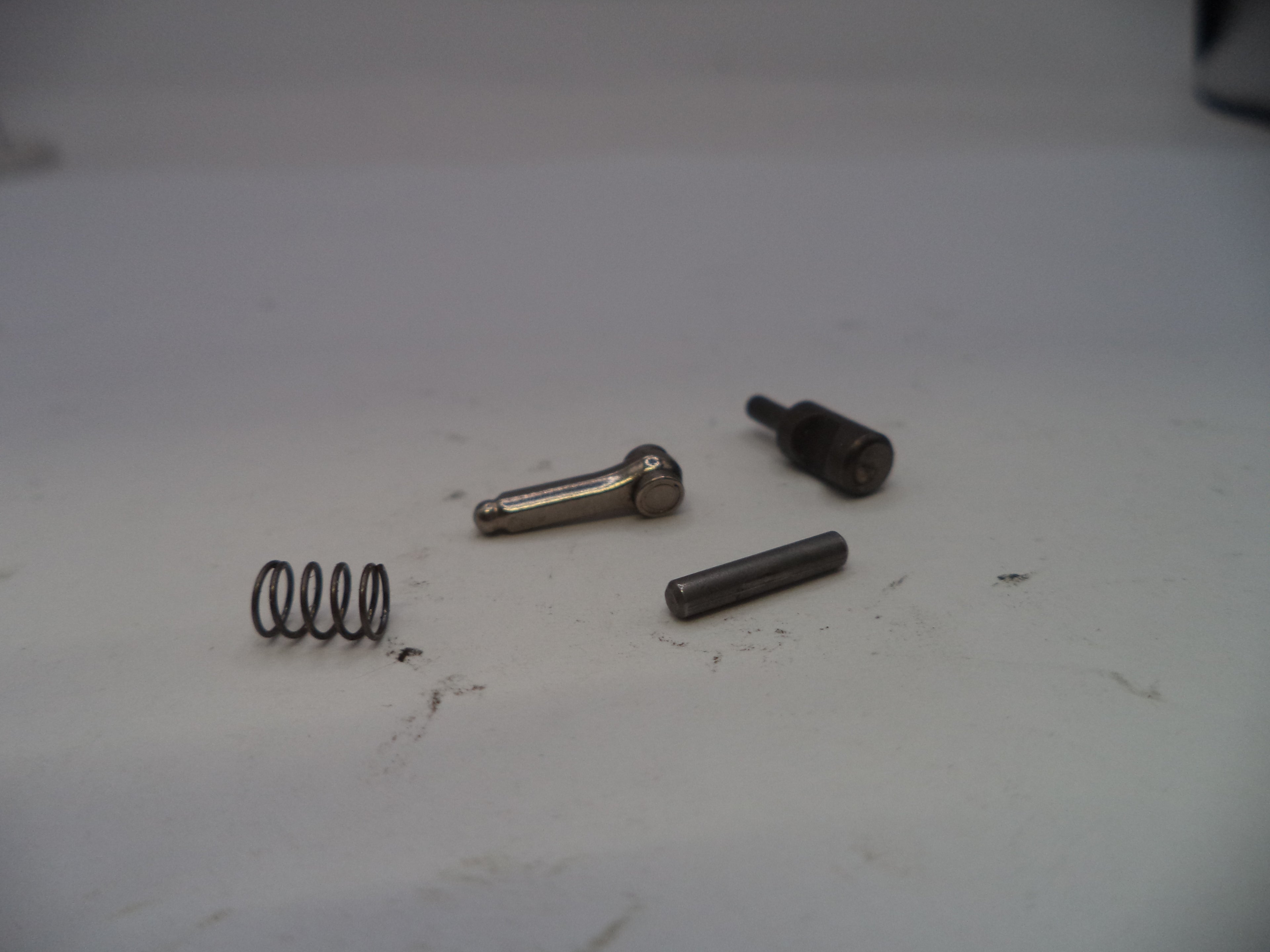 Four metal components on a white surface