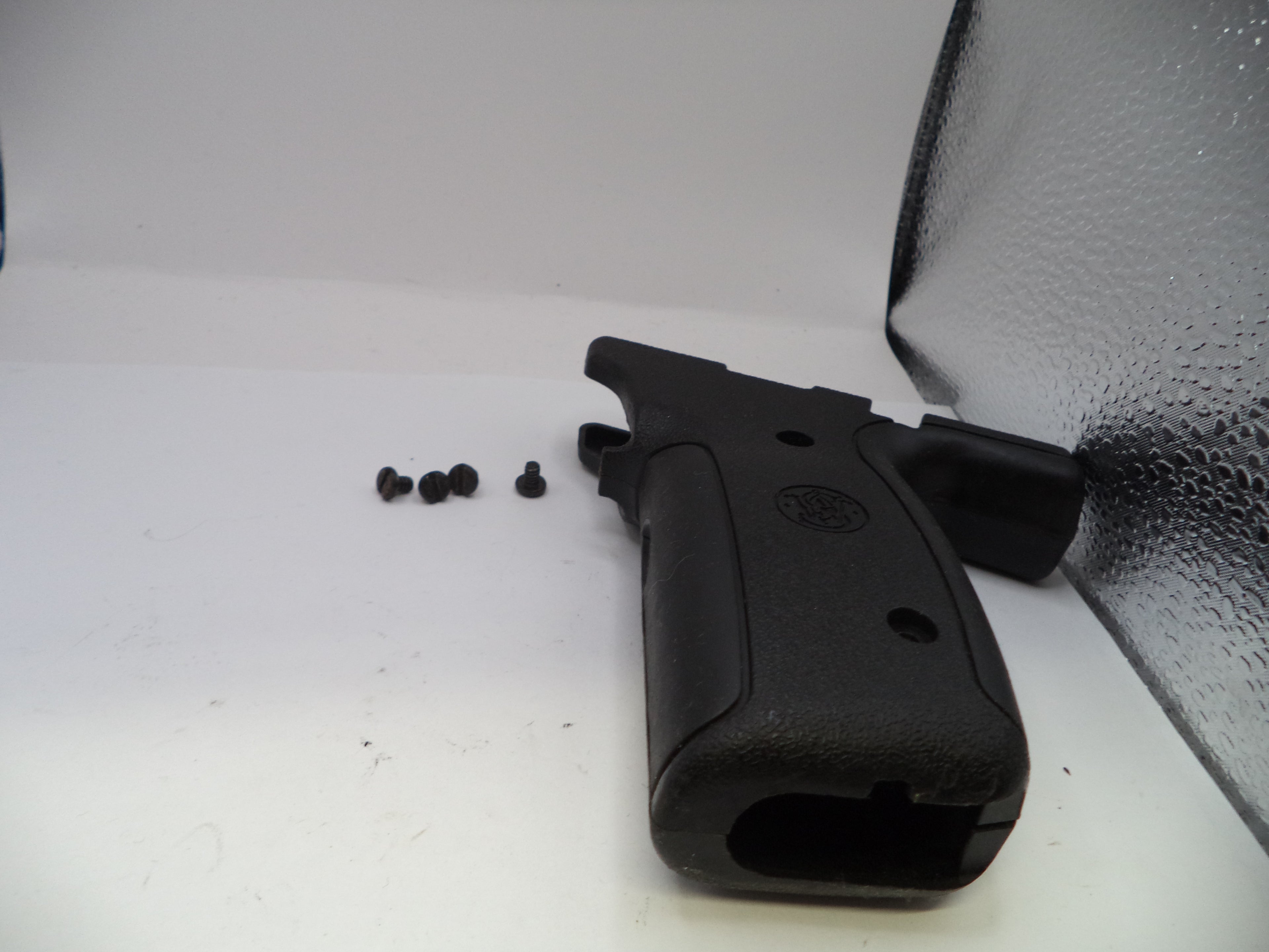 Black gun grip and screws on a white surface