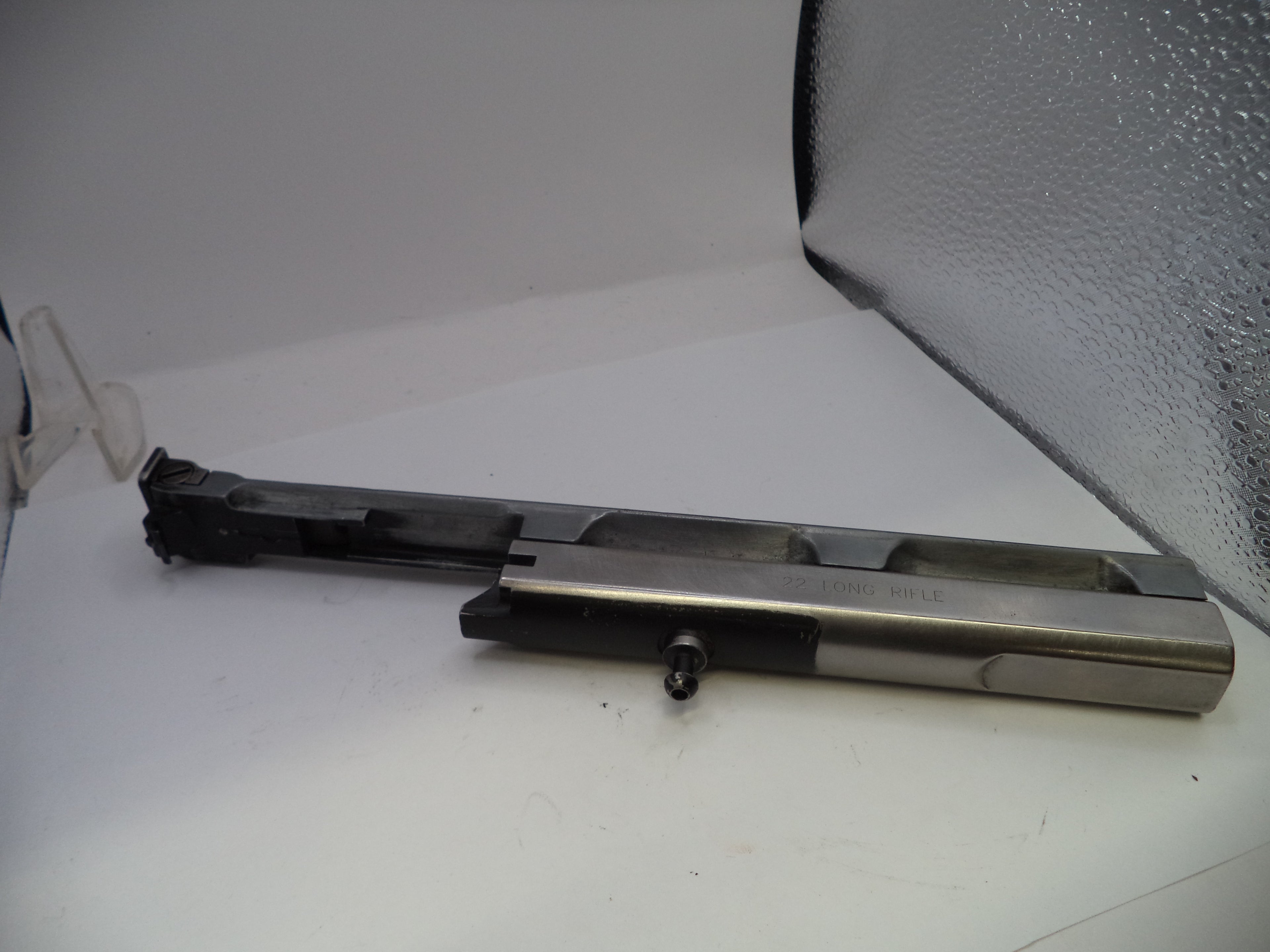 Metal component on a white surface with a textured gray background