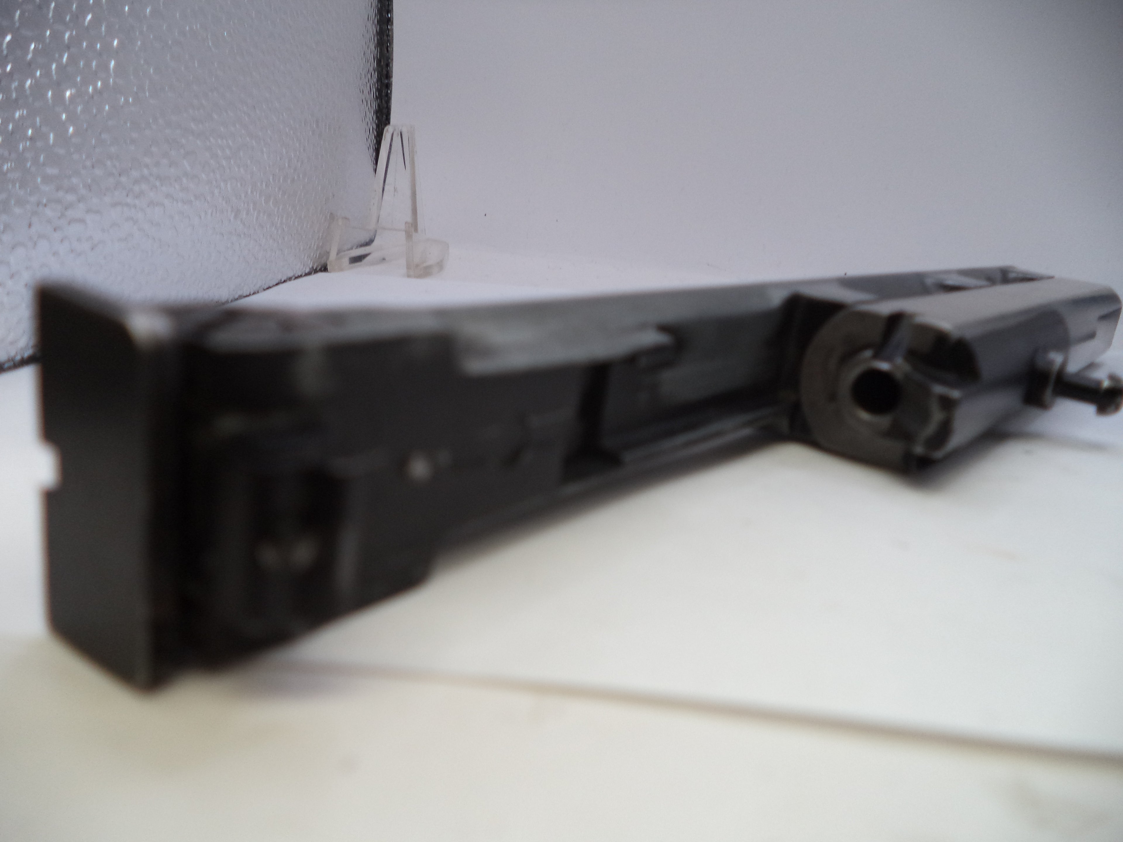 Black mechanical component on a white surface with a textured gray background