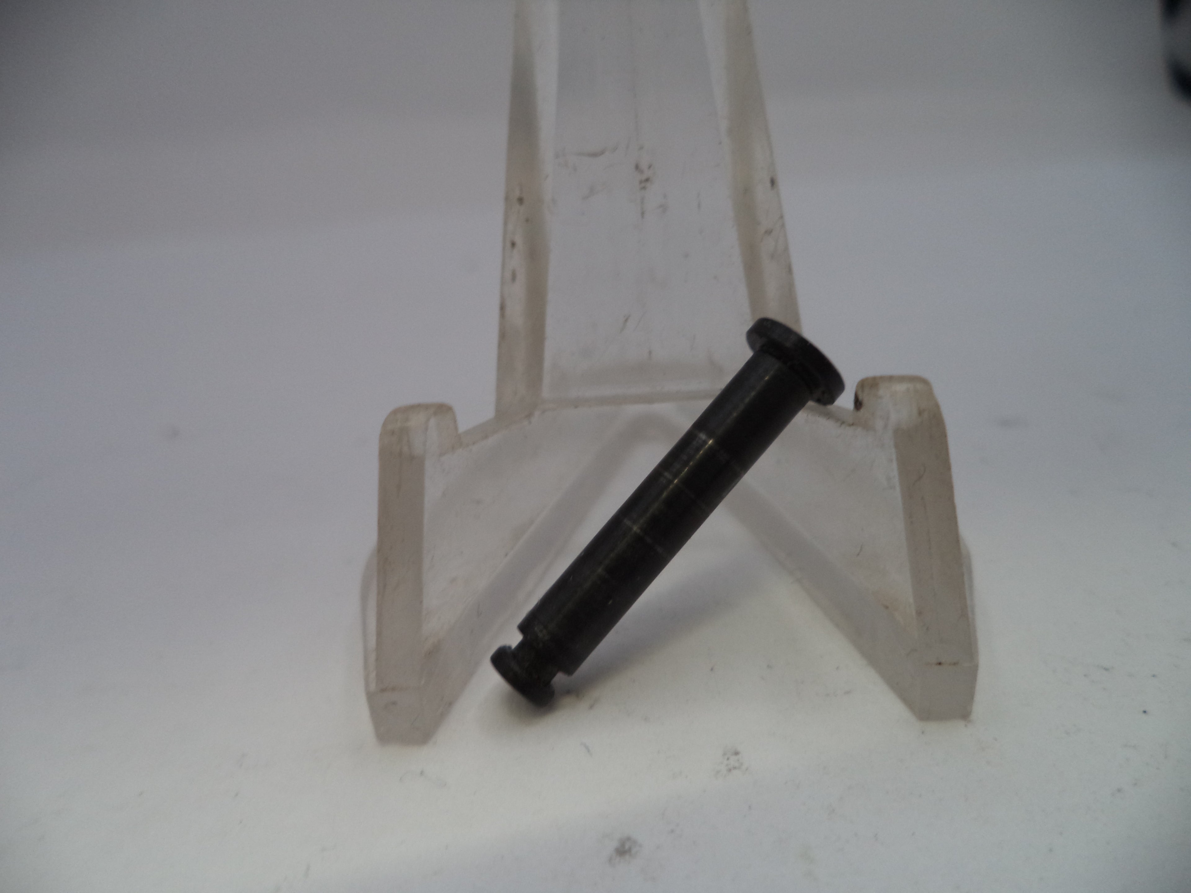 Black bolt on a small white easel against a plain background