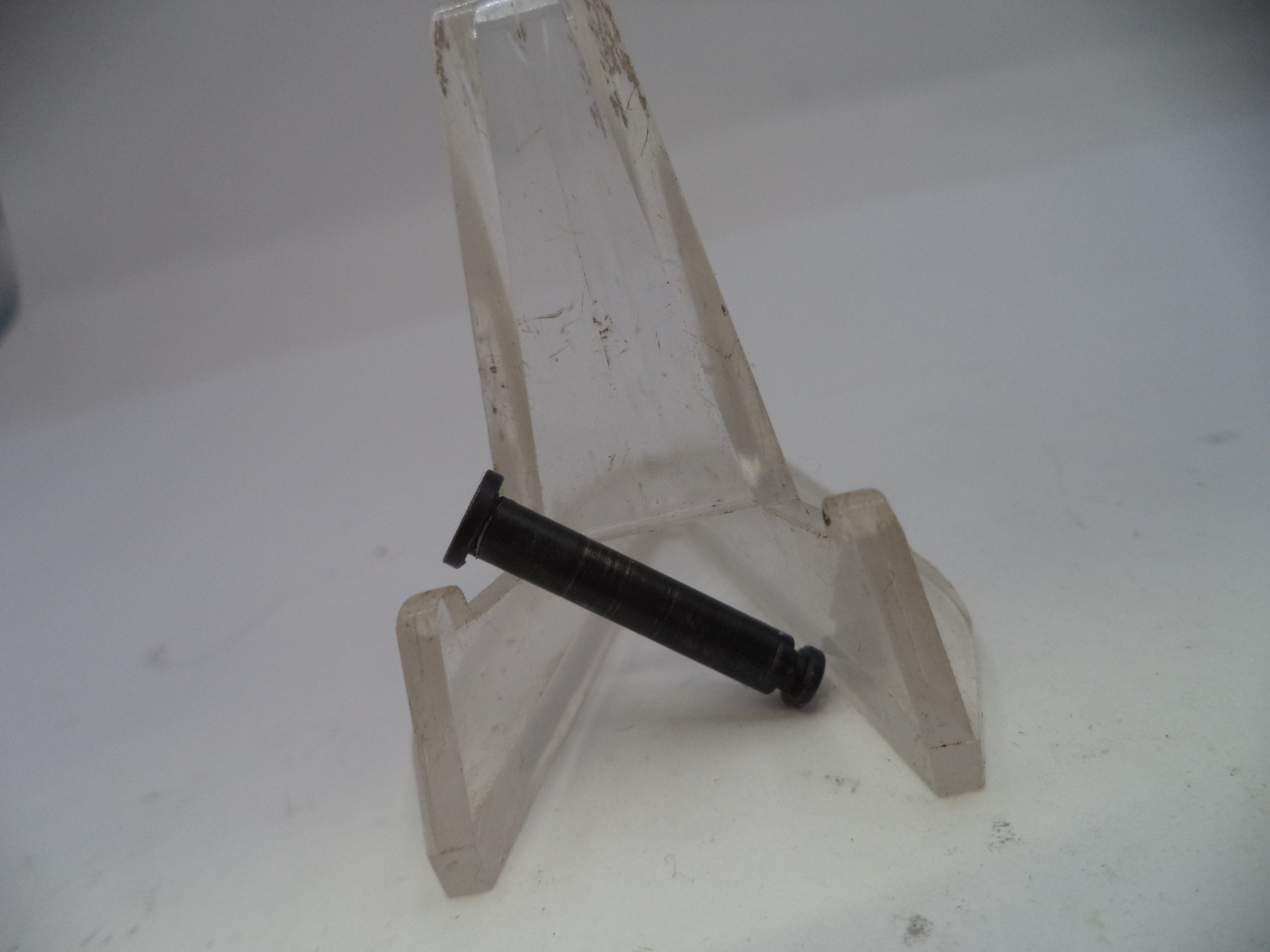 Black cylindrical object on a clear plastic stand against a white background