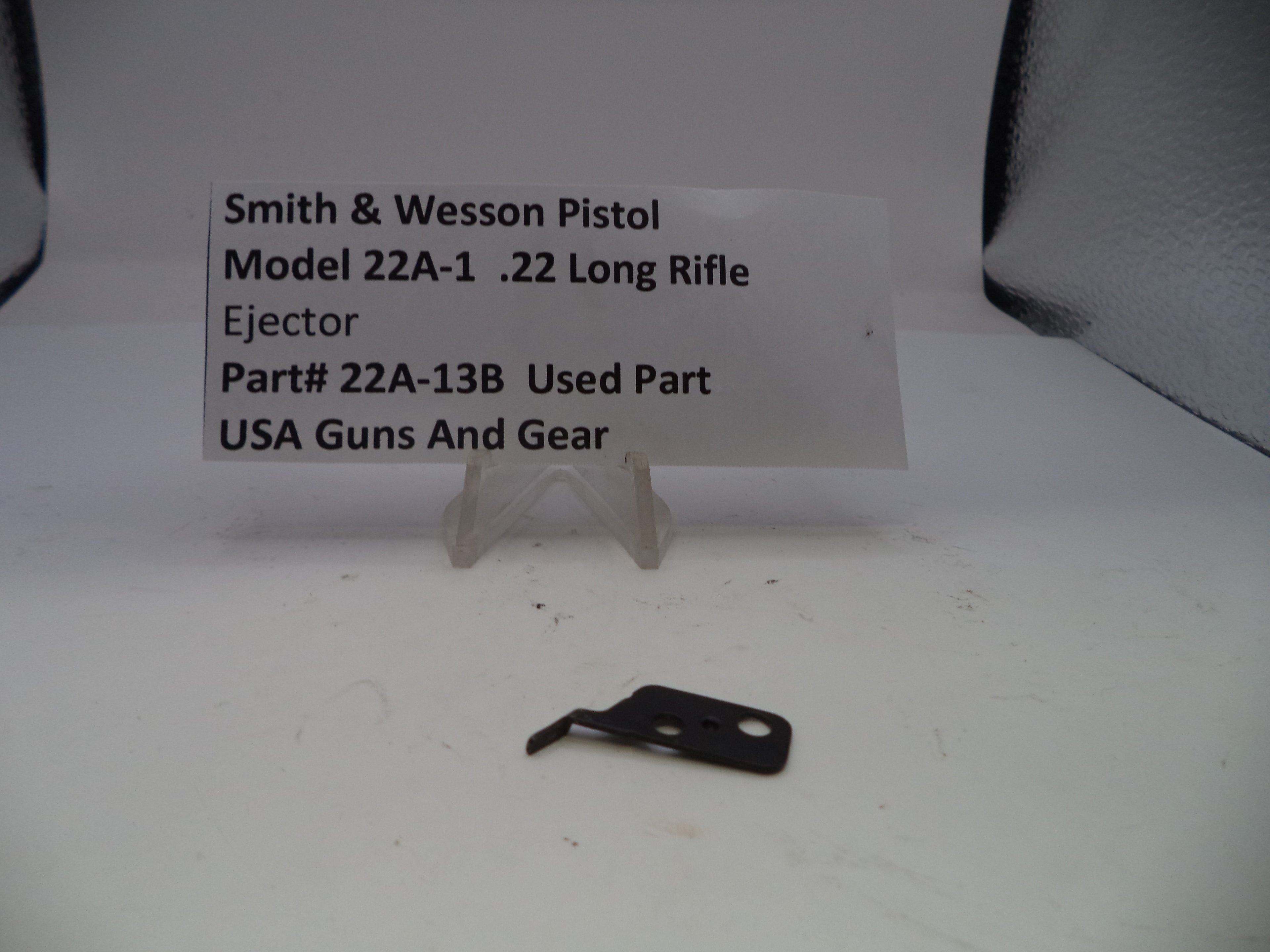 Smith & Wesson pistol ejection part on a white background with a label.