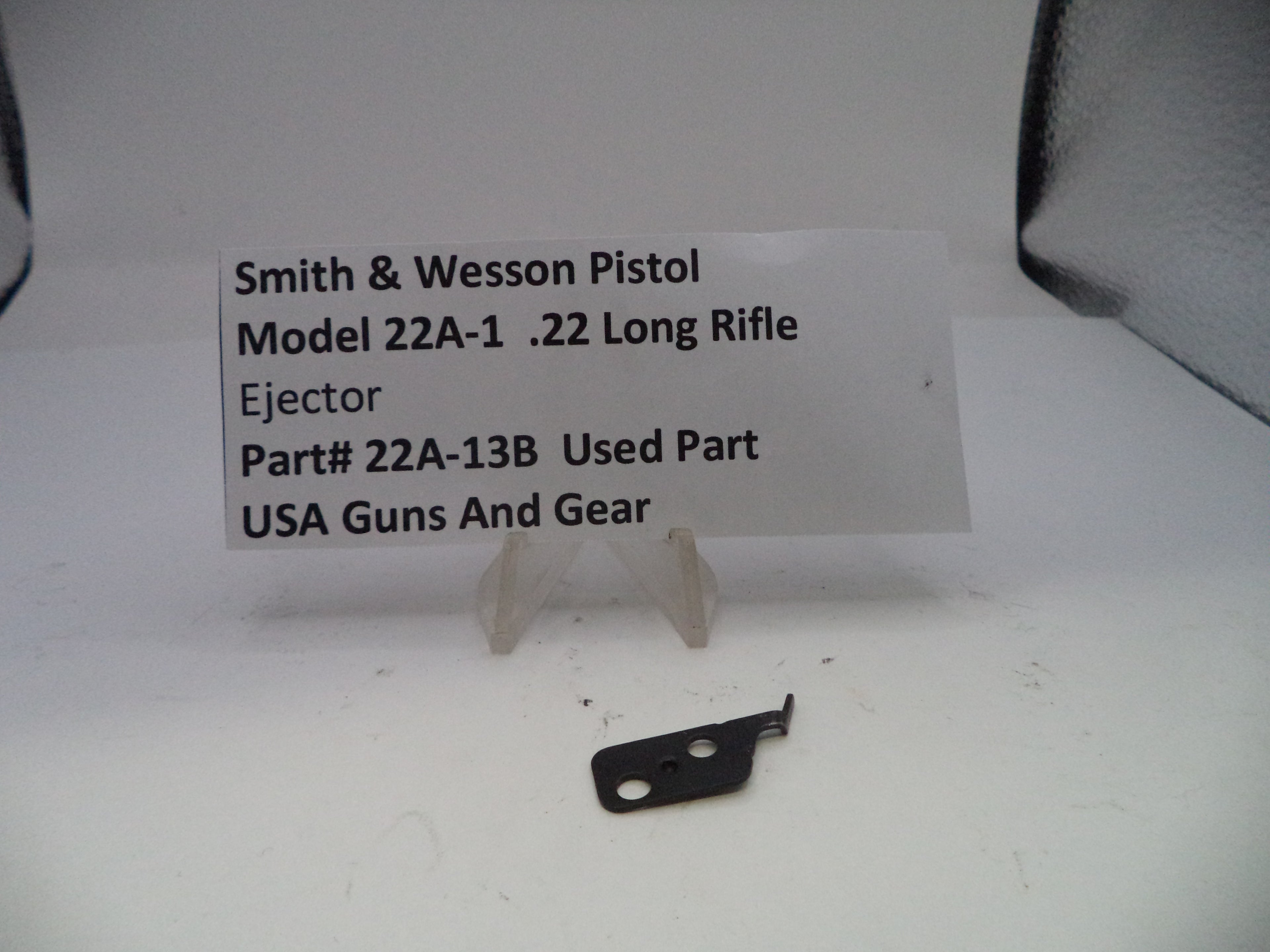 Smith & Wesson pistol ejection part on a white background with a label.