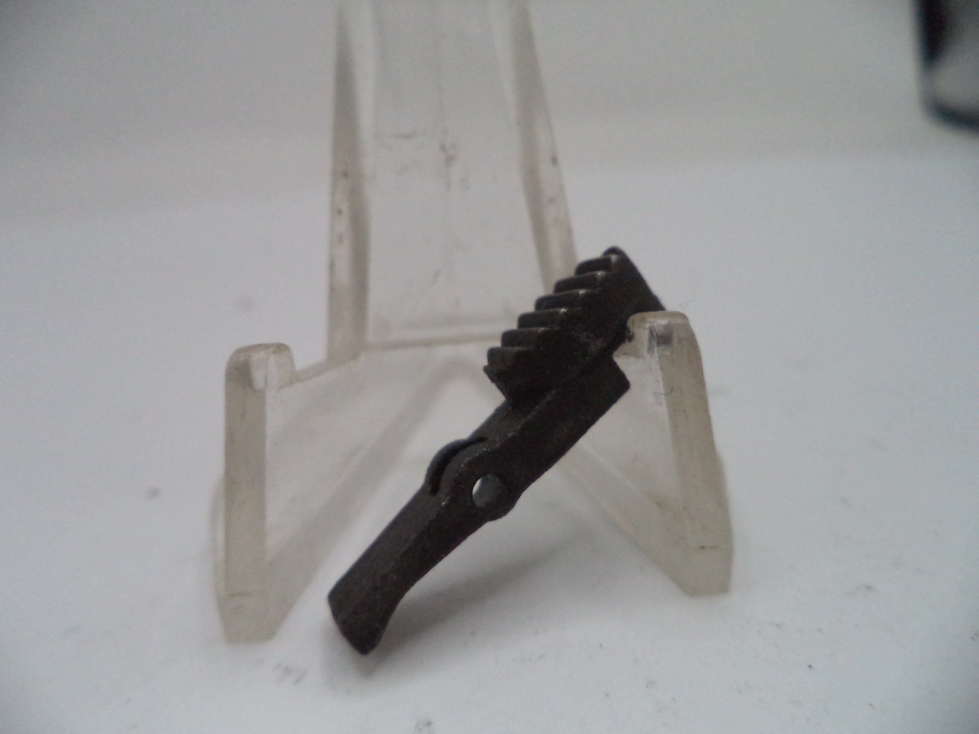 Metal bracket on a clear stand against a white background