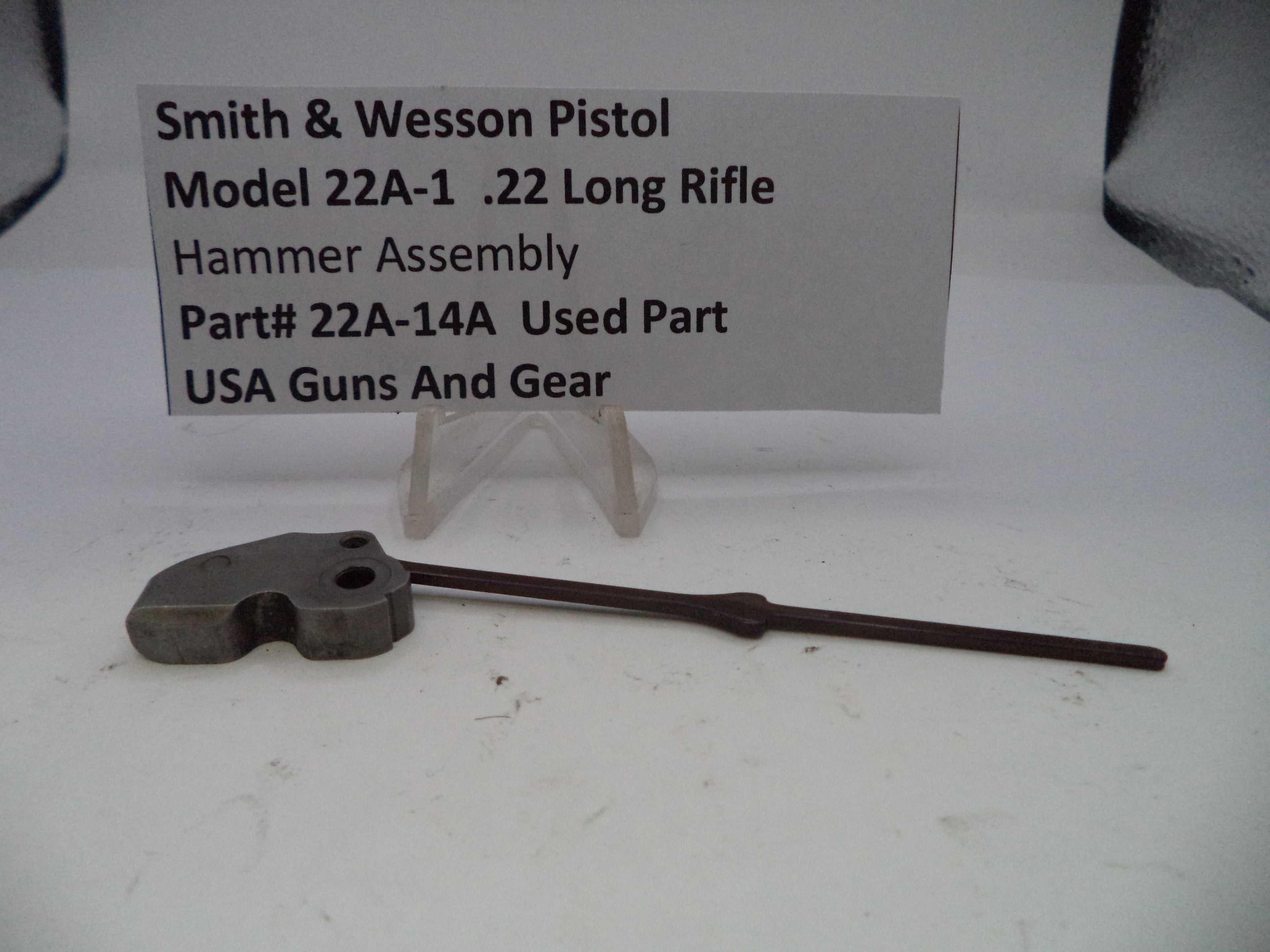 Smith & Wesson pistol hammer assembly on a white background with a label.