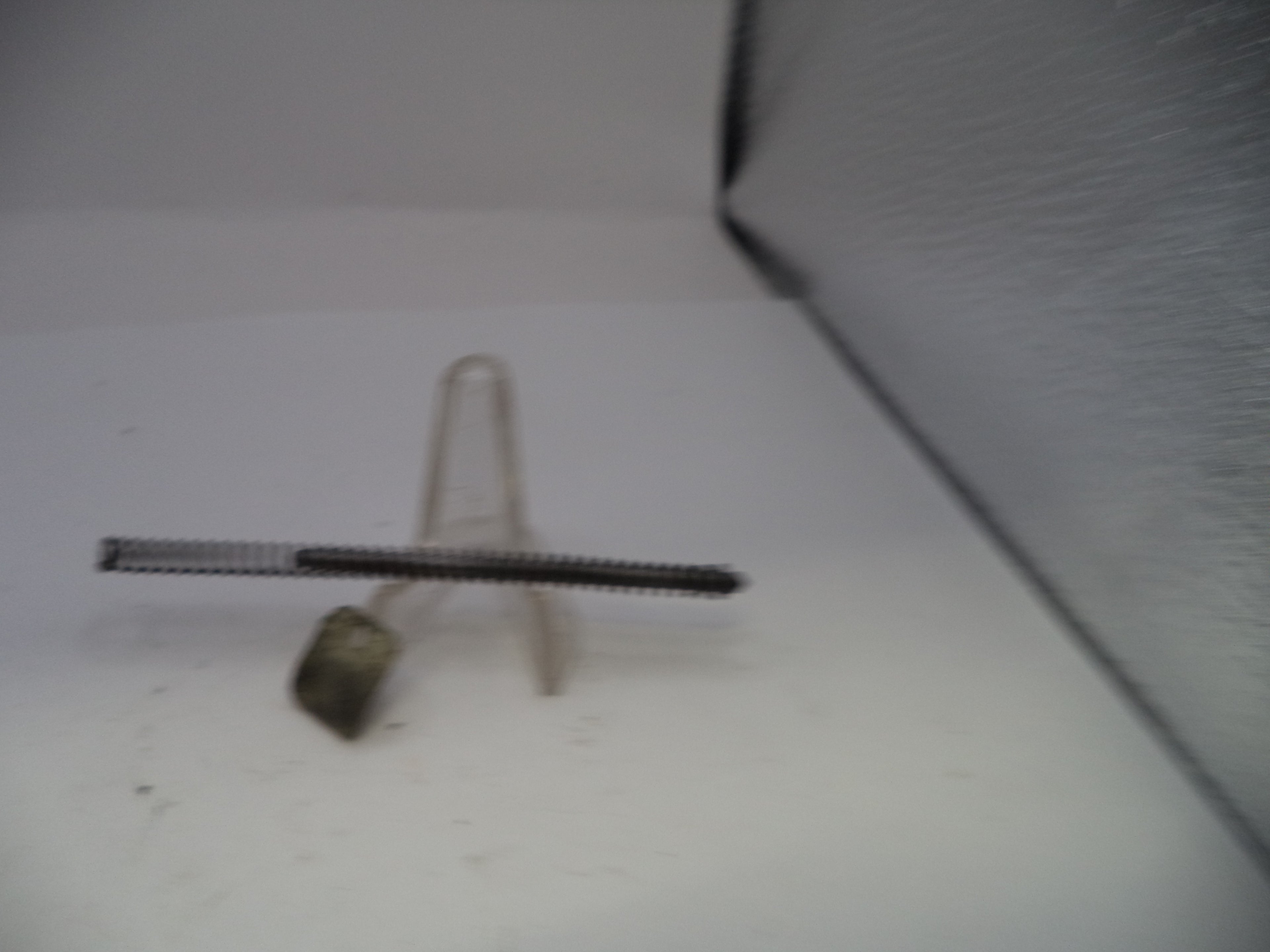 Metallic object on a white surface with a textured background