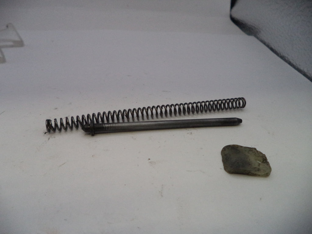 Metal spring and cylindrical object on a white surface with a small rock.
