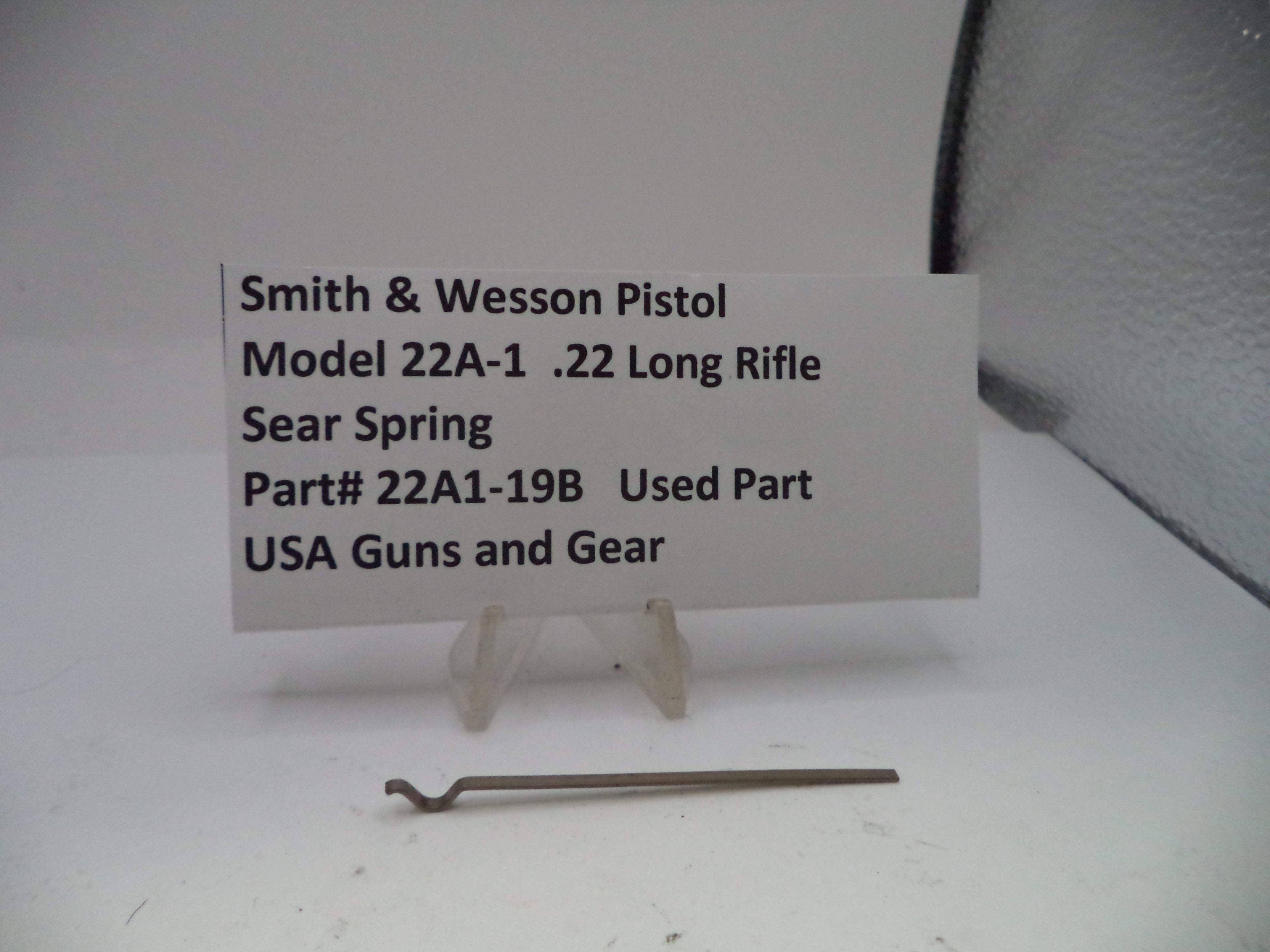 Smith & Wesson pistol part with a label on a white background