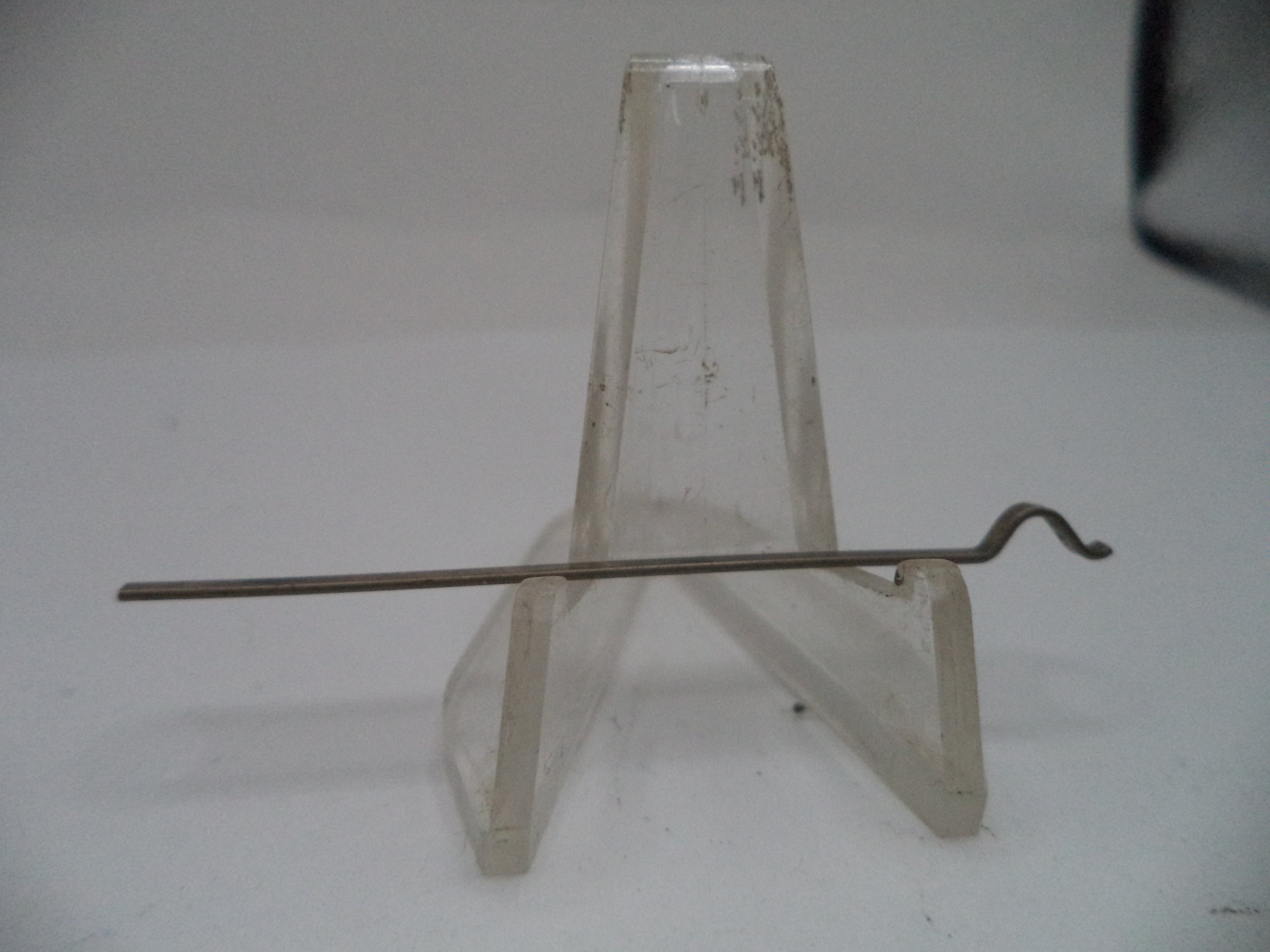 Metal rod on a clear plastic stand against a white background