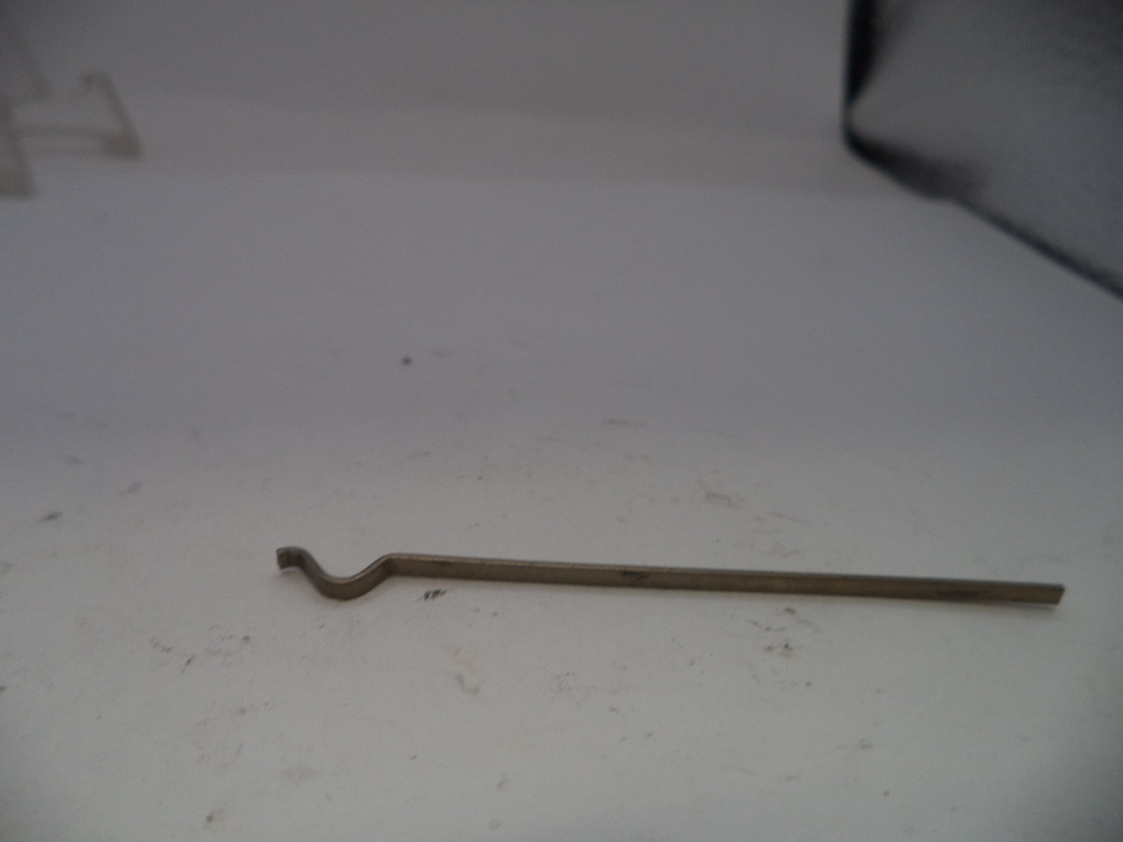 Metal tool on a white surface with a dark corner