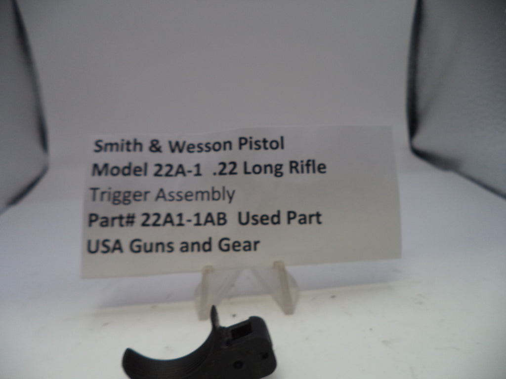 Smith & Wesson pistol trigger assembly on a stand with descriptive text card.