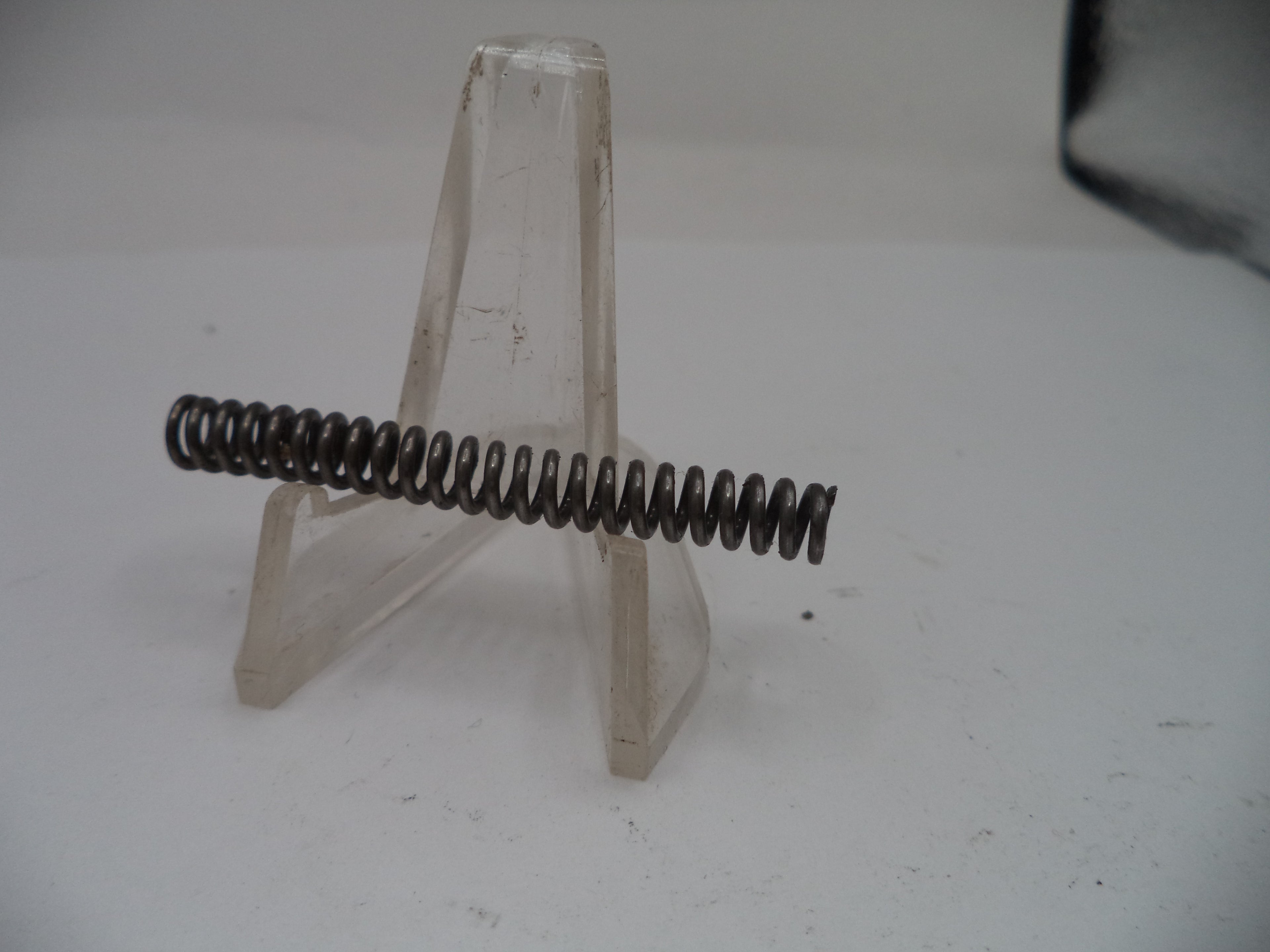 Metal spring on a clear stand against a white background
