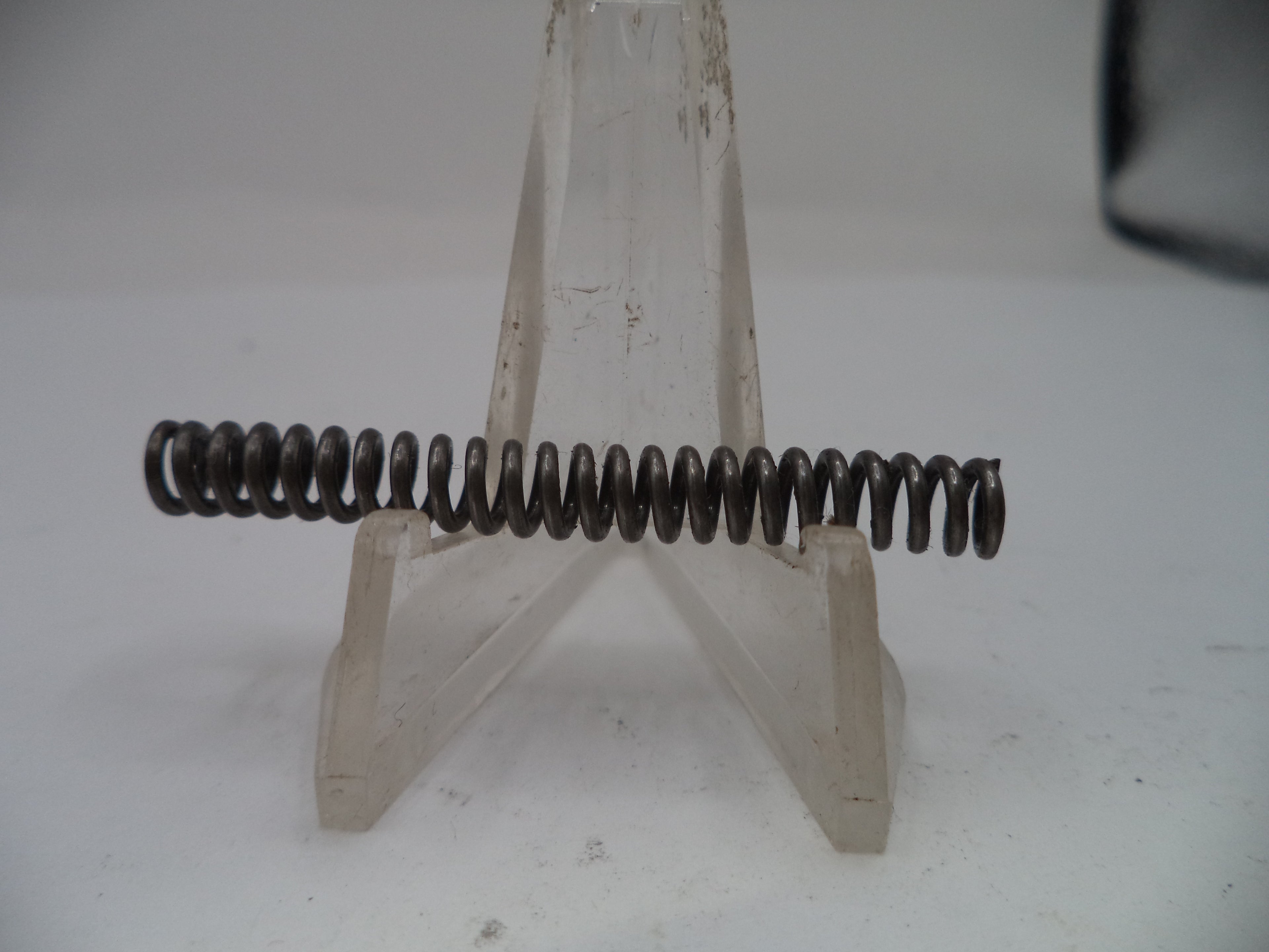Metal spring on a stand against a plain background