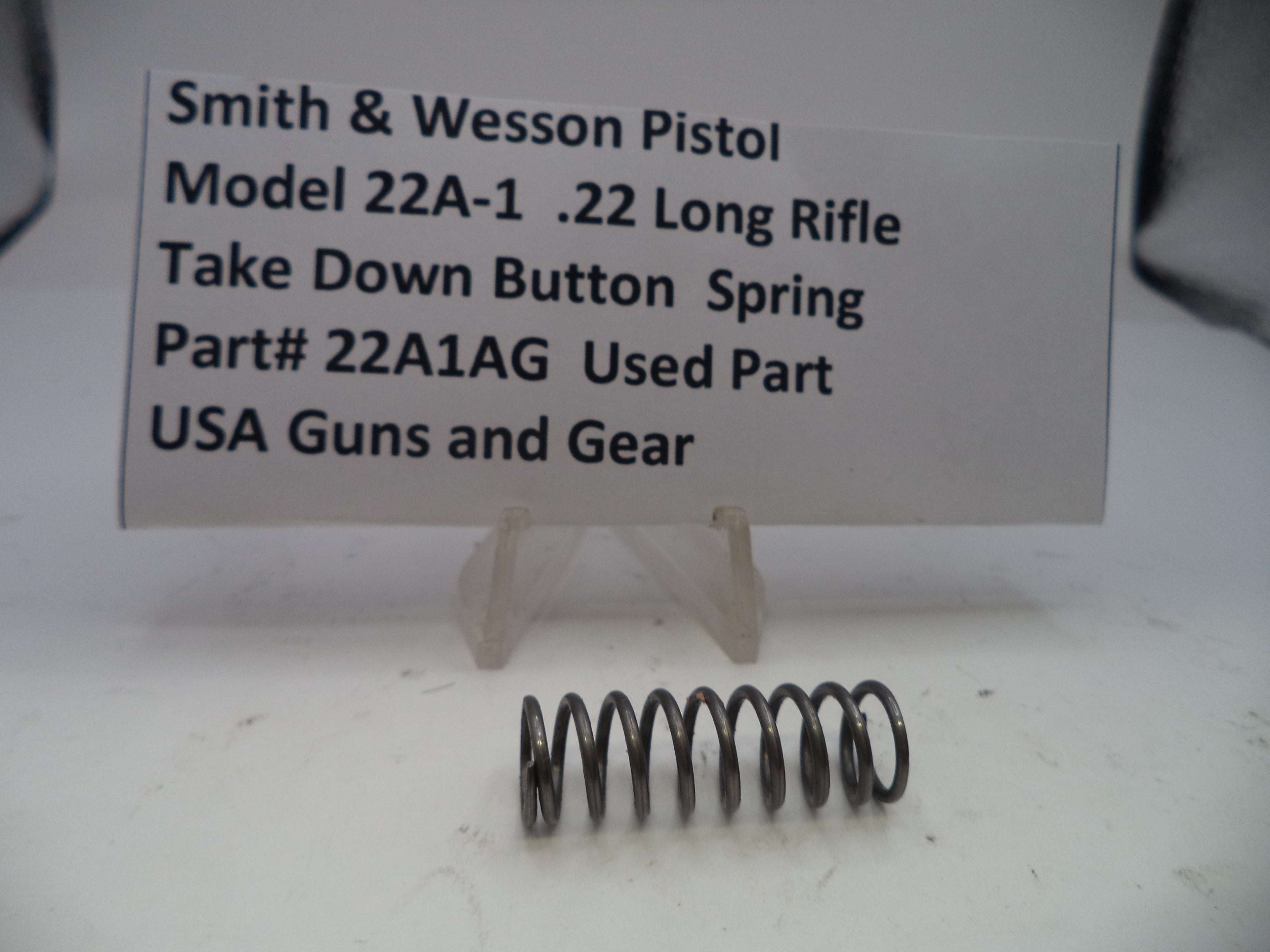 Smith & Wesson Pistol Model 22A-1 .22 Long Rifle take down button spring on a white background with a label.